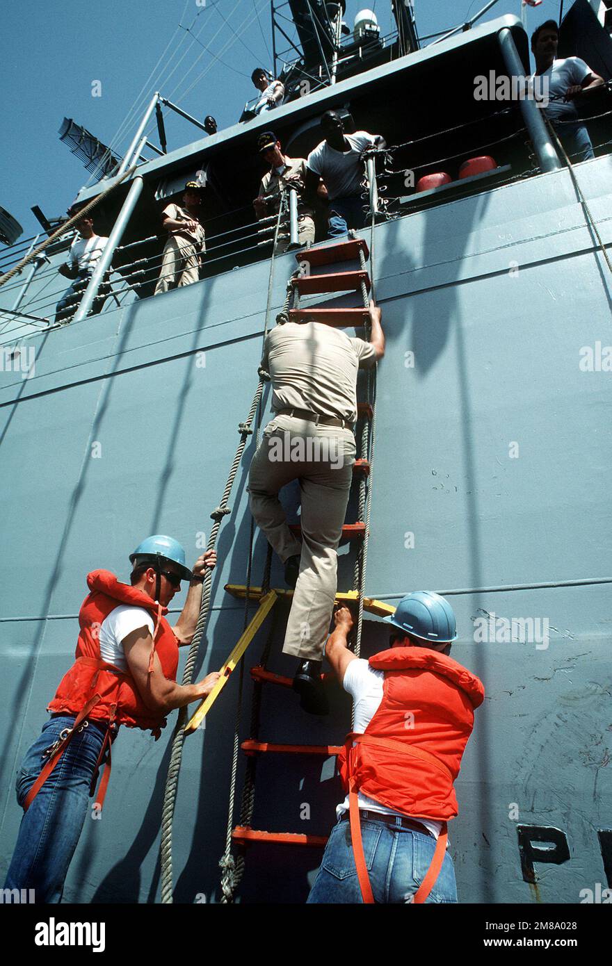 LT. Dan Taylor verhandelt über die gebrochenen Sprossen einer Jacob's Leiter, während er von der geführten Raketenfregatte USS NICHOLAS (FFG-47) in ein Walboot steigt. Taylor, ein Navy Liaison Officer (NLO), wird auf einen umgefleckten kuwaitischen Tanker verlegt, um als Marinevertreter an Bord des Schiffes während einer ernsten Konvoi-Mission zu fungieren, bei der die Tanker von US-Marineschiffen durch die Golfgewässer begleitet werden. Betreff Betrieb/Serie: ERNSTWILLE Land: Unbekannt Stockfoto