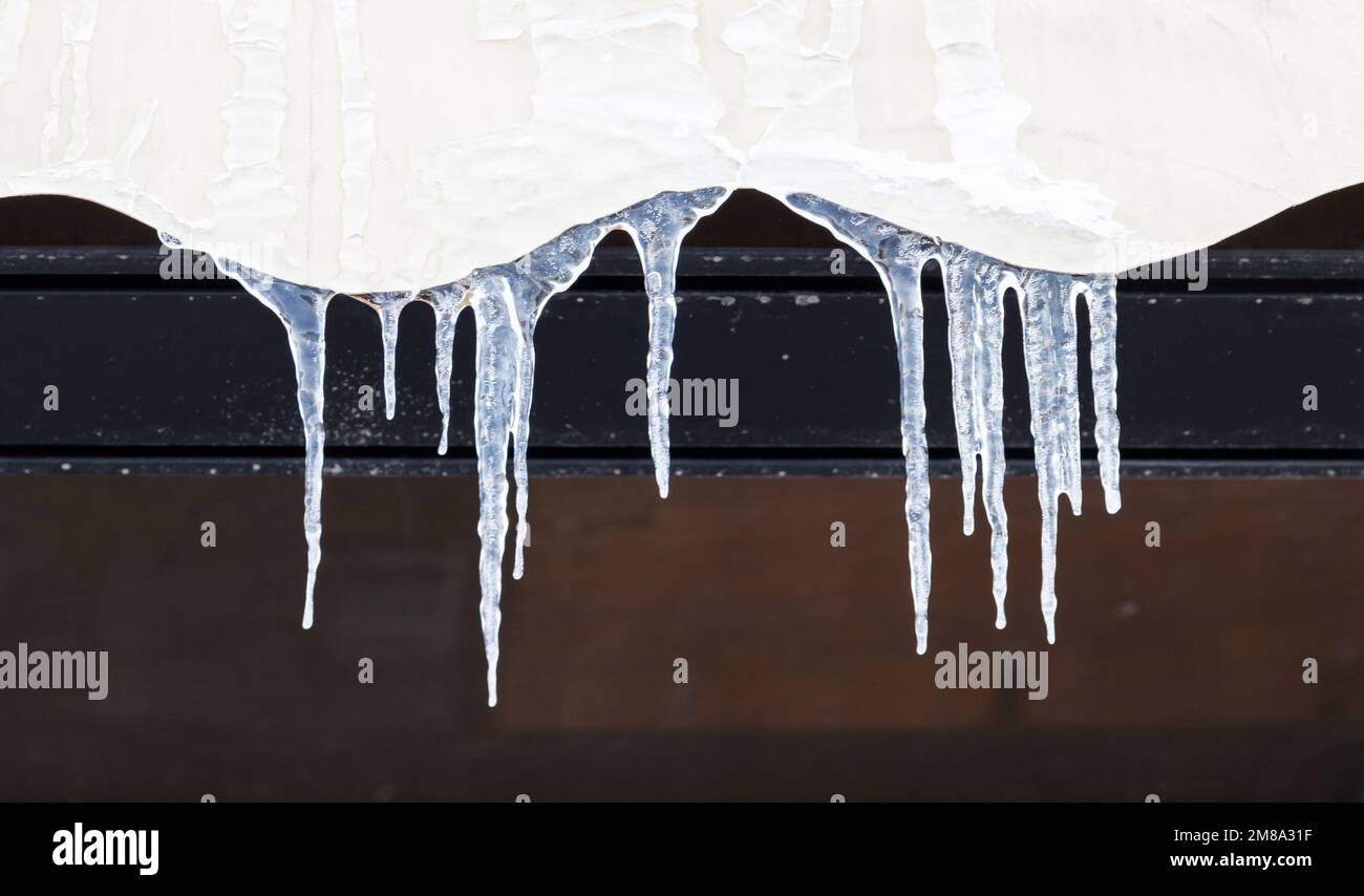 Eiszapfen hängen auf einem Hausdach, Nahaufnahme mit selektivem Weichzeichner Stockfoto