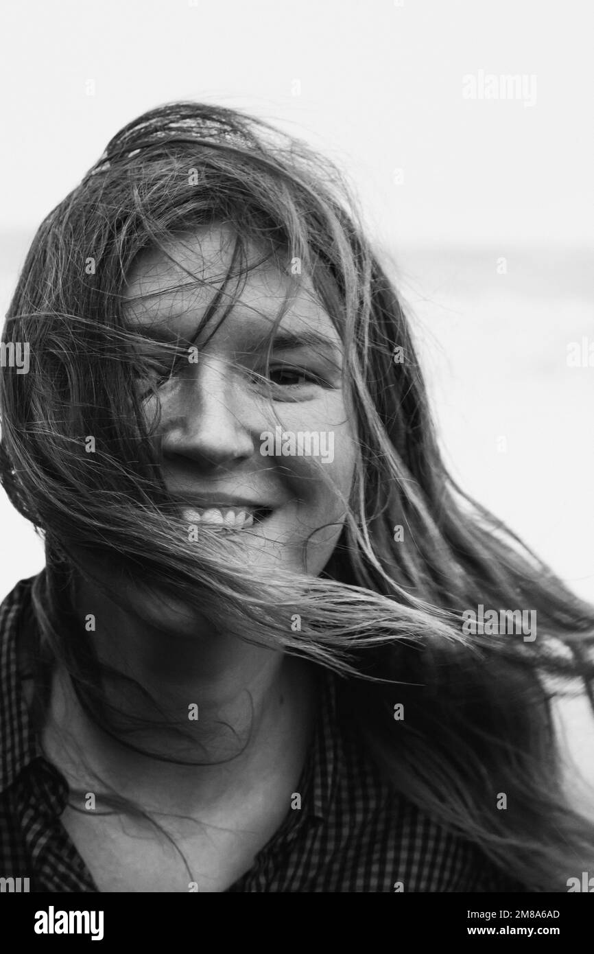 Nahaufnahme einer fröhlichen Frau mit unordentlichem Haar im Schwarzweiß-Porträt im Freien Stockfoto