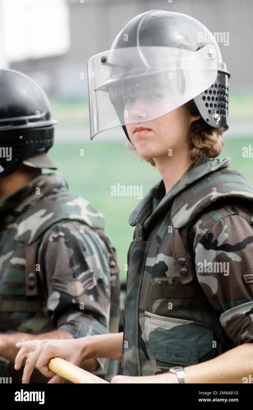 Ausgestattet mit Aufruhr-Ausrüstung steht AIRMAN Hope Crider der 3345. Sicherheitspolizei-Staffel (3345. SPS) in einer Reihe von Polizisten nahe Gate 6 auf der Basis. Sie gehört zu den 3345. SPS-Mitarbeitern, die aus der Chanute Air Force Base, Illinois, für den Exercise Creek war eingeflogen sind. Betreff Operation/Serie: CREEK WARRIOR '88 Base: Sembach Air Base Land: Deutschland / Deutschland (DEU) Stockfoto