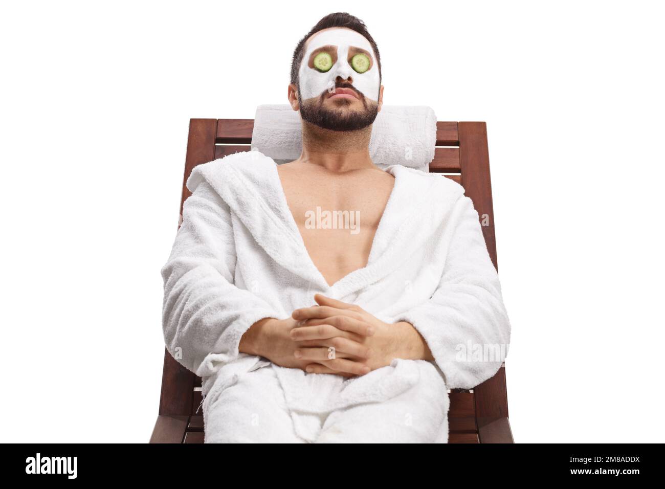 Porträt eines Mannes mit Gesichtsmaske und Gurken über Augen isoliert auf weißem Hintergrund Stockfoto