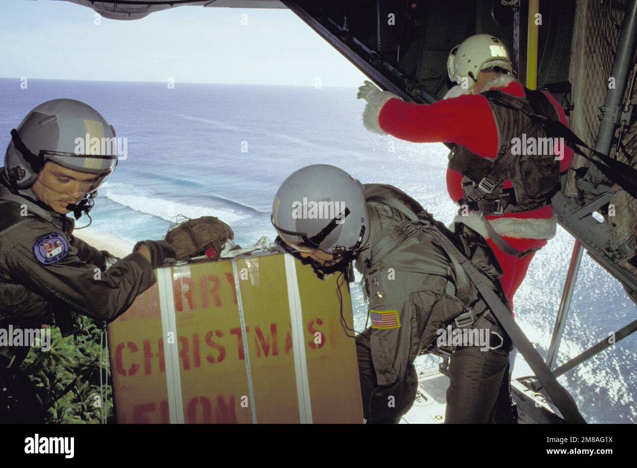 Das Personal der taktischen Lufttransport-Geschwader 345. und 21. bereitet sich darauf vor, ein Paket aus dem Frachtraum ihres C-130-Flugzeugs Hercules zu entladen, während der Weihnachtsmann (MGEN Alexander K. Davidson, Commander, 22. Air Force) bereitsteht. Gespendete Weihnachtsgeschenke werden mit dem Fallschirm auf lokale Inseln abgesprungen. Staat: FS Micronesia (FM) Land: Vereinigte Staaten von Amerika (USA) Stockfoto