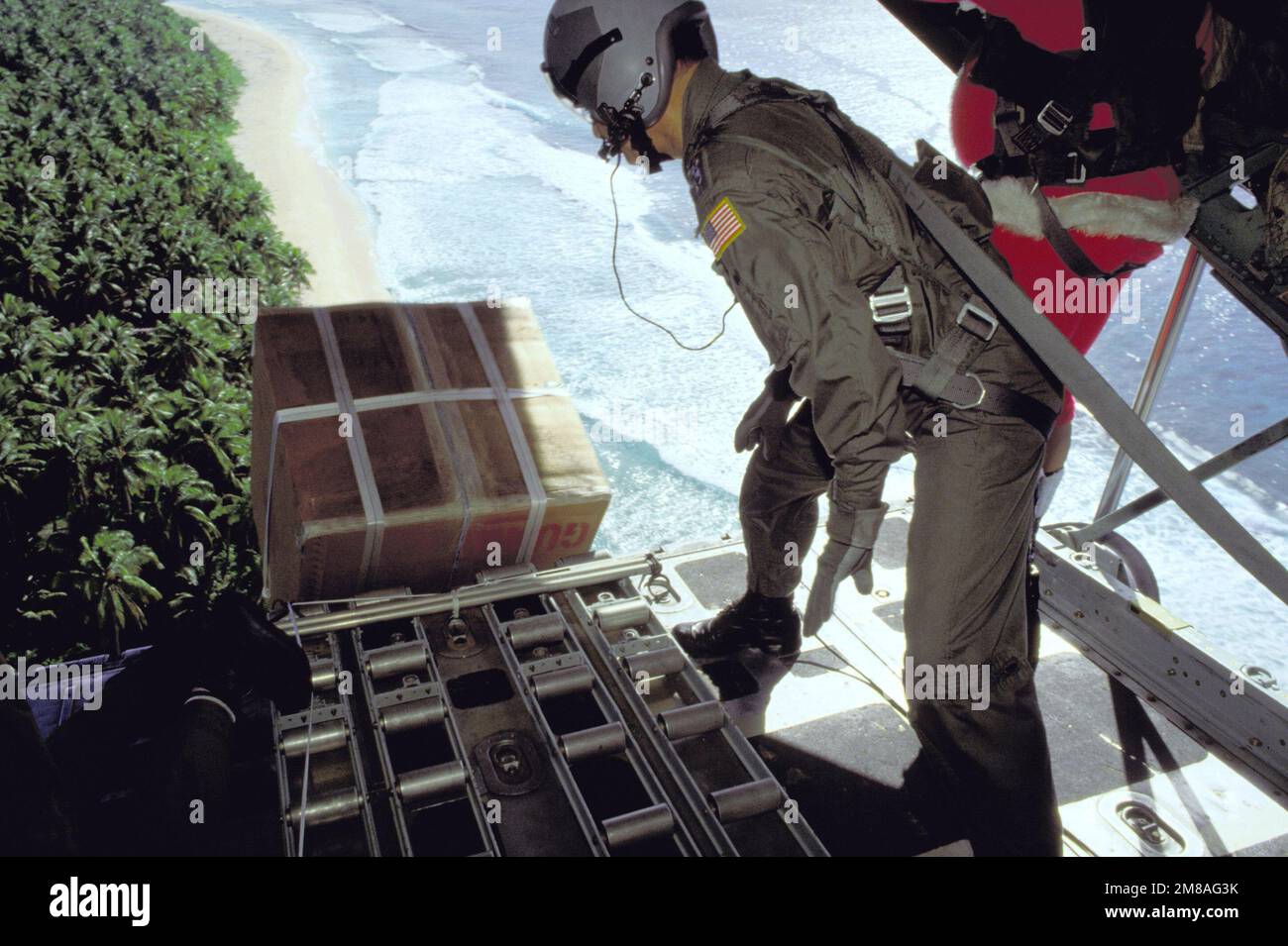 Personal der taktischen 345.- und 21.-Flugstaffeln lässt ein Paket aus dem Frachtraum eines C-130-Herkules-Flugzeugs raus. Gespendete Weihnachtsgeschenke werden mit dem Fallschirm auf lokale Inseln abgesprungen. Staat: FS Micronesia (FM) Land: Vereinigte Staaten von Amerika (USA) Stockfoto