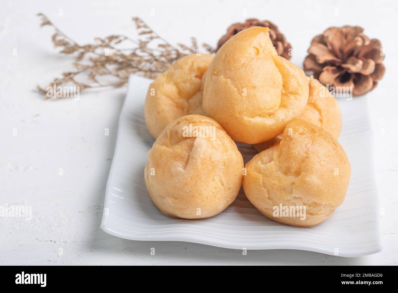 eclair mit Vanille-Custard-Füllungen auf weißer Platte auf weißem Hintergrund Stockfoto