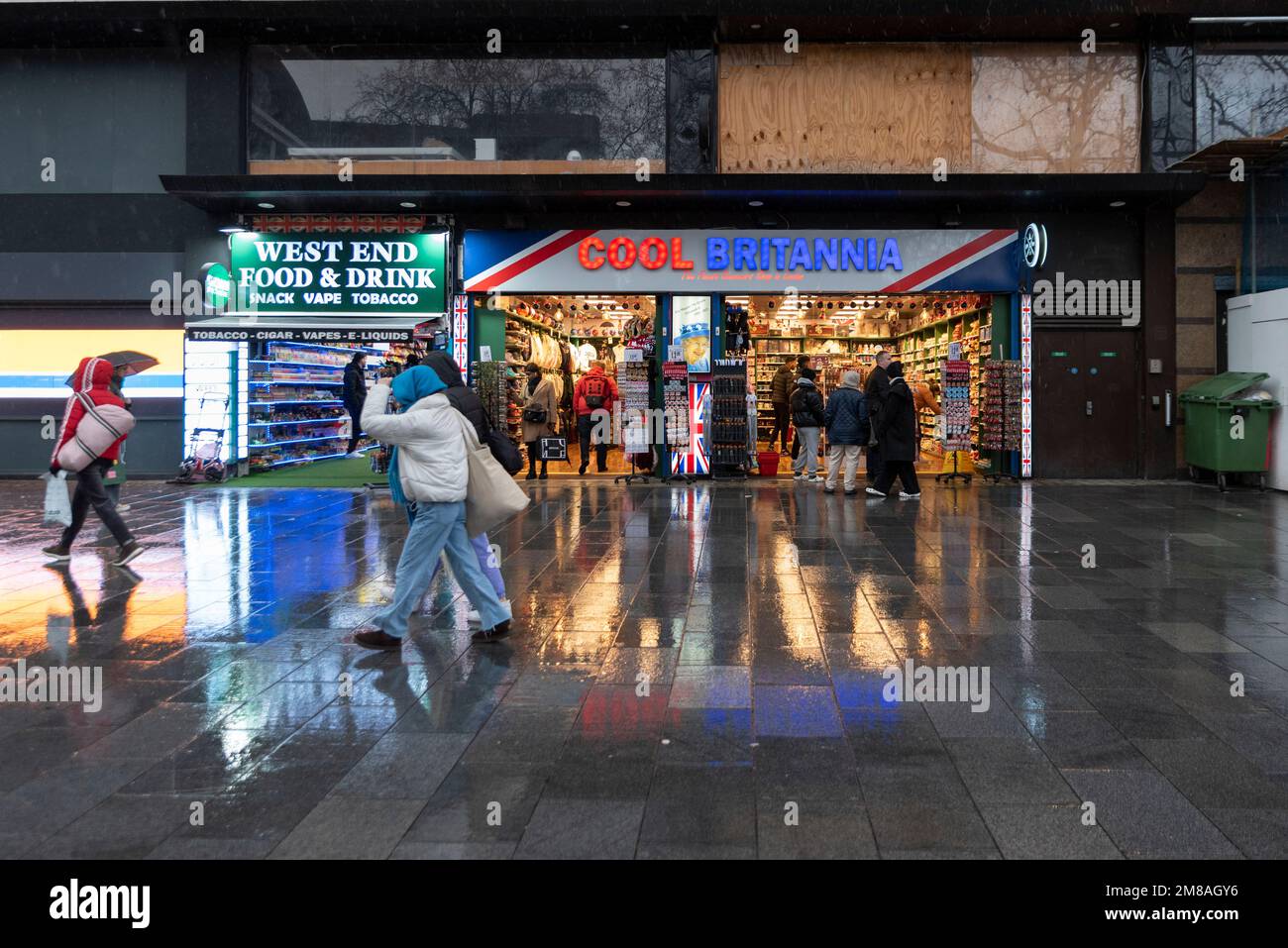 Cooles Britannia Souvenir Shop, Leicester Square, London, Großbritannien. Britischer Tourismus. Vorderseite anzeigen. Vorne lagern. Leute, die an einem nassen, regnerischen Winterabend vorbeigehen Stockfoto