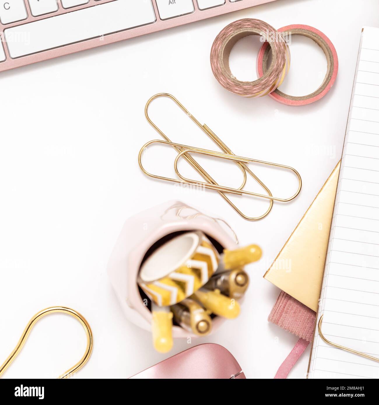 Femininer Schreibtisch mit goldenen und pinkfarbenen Schreibwaren, einschließlich Tastatur und Maus Stockfoto