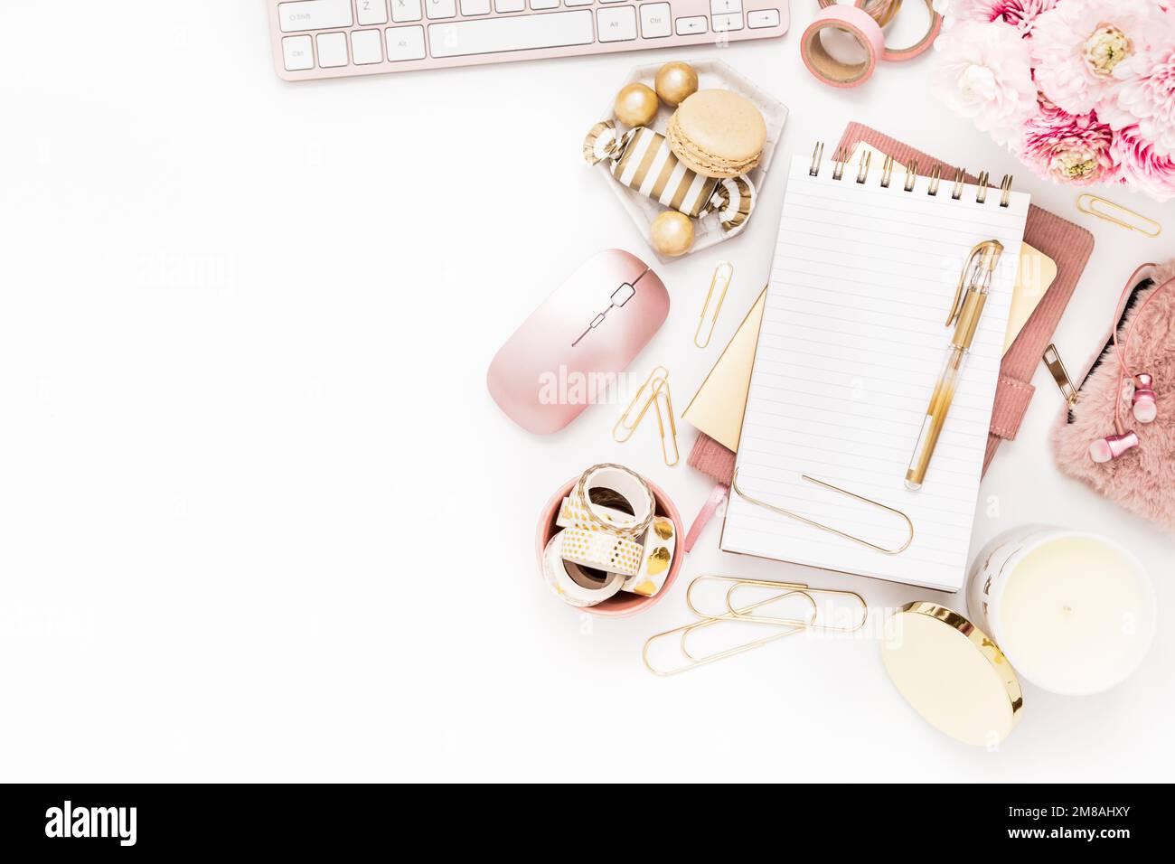 Femininer Schreibtisch mit goldenen und pinkfarbenen Schreibwaren, einschließlich Tastatur und Maus Stockfoto
