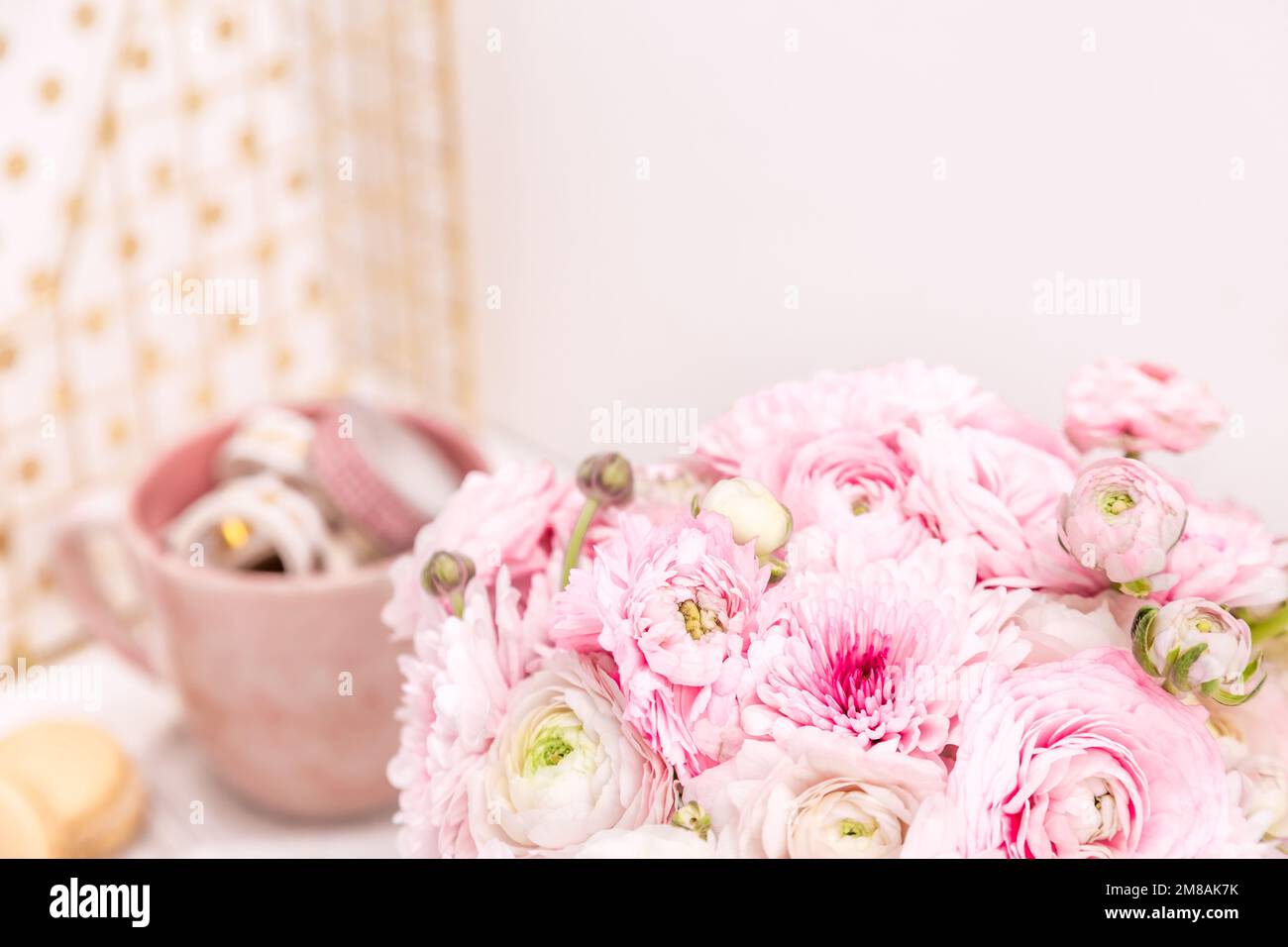 Femininer Schreibtisch mit goldenen und pinkfarbenen Schreibwaren, einschließlich frischer Blumen Stockfoto