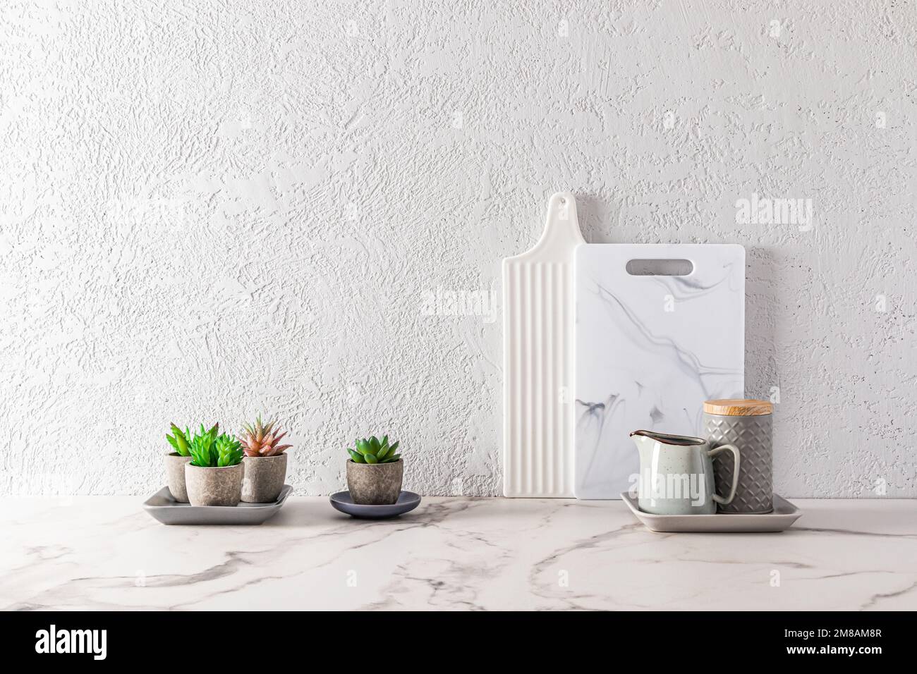 Teil der Inneneinrichtung einer modernen Küchenablage mit weißen Marmorplatten und Sukkulenten in Blumentöpfen. Minimalismus Stockfoto
