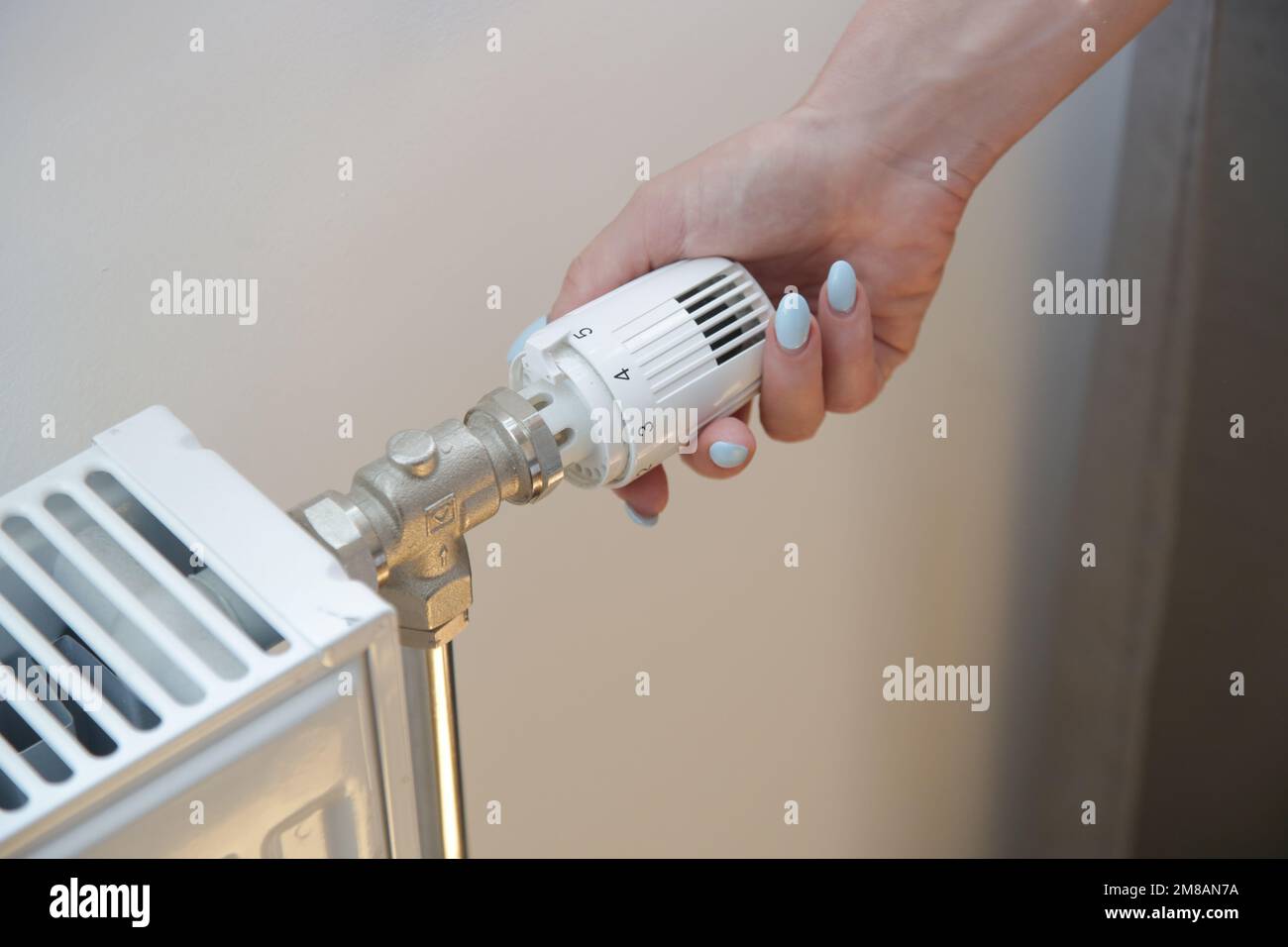 Frauenhand stellt Heizkörperthermostatventil ein, steuert Zentralheizung Stockfoto
