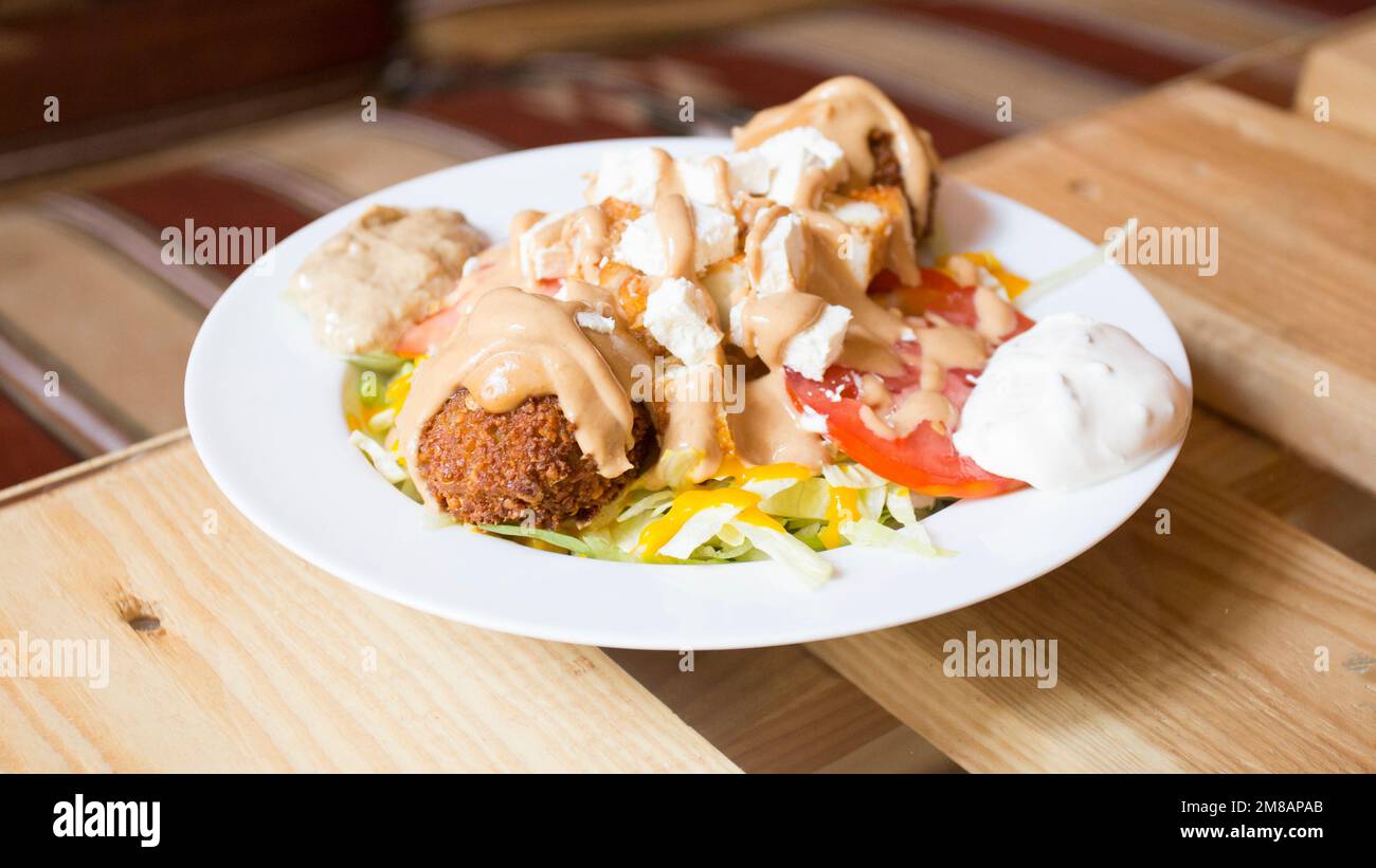 Falafel-Kombi-Gericht mit Gemüse. Faláfel oder falafel​ ist eine Kichererbse oder Bohnenkrokette. Es wird normalerweise im Nahen Osten konsumiert. Stockfoto