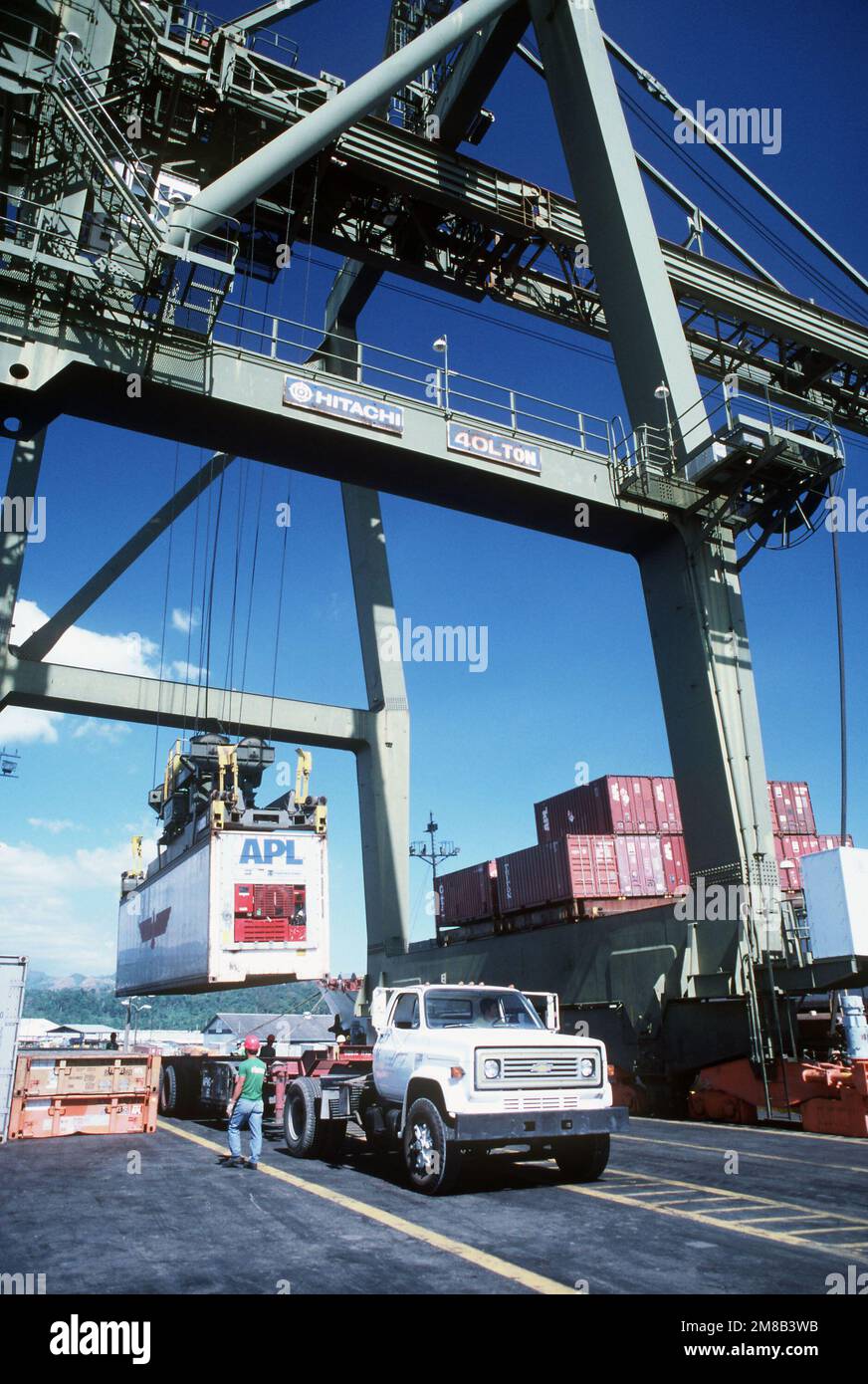 Ein Container, der vom vom militärischen Sealift-Kommando entladenen Containerschiff Präsident Taft entladen wurde, wird mit einem 40-Tonnen-Kran auf einen Anhänger abgesenkt. Basis: Naval Supply Depot, Subic Bay Bundesstaat: Luzon Land: Philippinen (PHL) Stockfoto