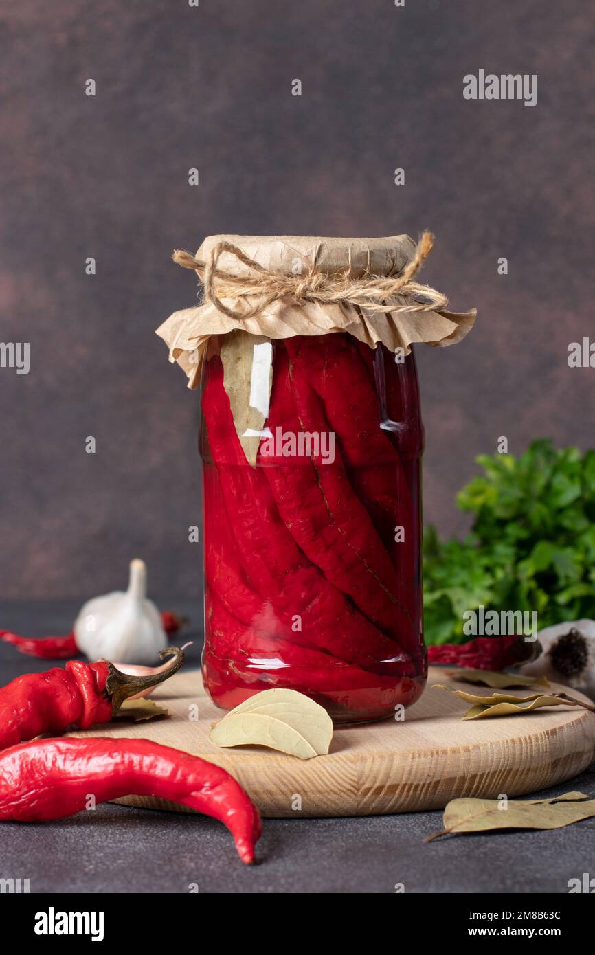 Hausgemachte eingelegte Chilischoten mit Knoblauch im Glas auf Holzbrett Stockfoto