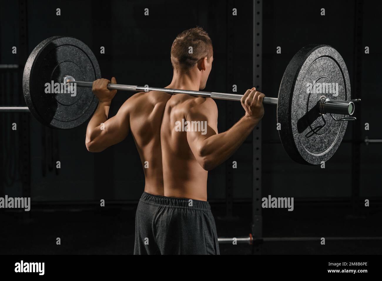 Ein Mann, der Rückenhocker-Übungen mit einer Hantel macht. CrossFit-Training im Fitnessstudio. Stockfoto