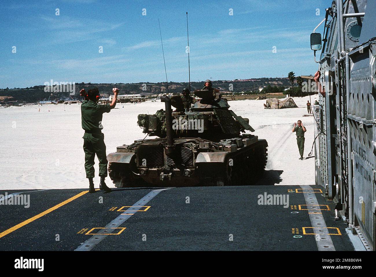 Die Signale eines Mannes an Bord eines Air Cushion Landing Craft (LCAC) werden an den Fahrer eines Marine M-60 Hauptpanzers weitergeleitet, der nach einer amphibischen Kriegsführung am Breakers Beach die Bugrampe des Schiffes zurückfährt. Basis: Marineflugstation, Nordinsel Bundesstaat: Kalifornien (CA) Land: Vereinigte Staaten von Amerika (USA) Stockfoto