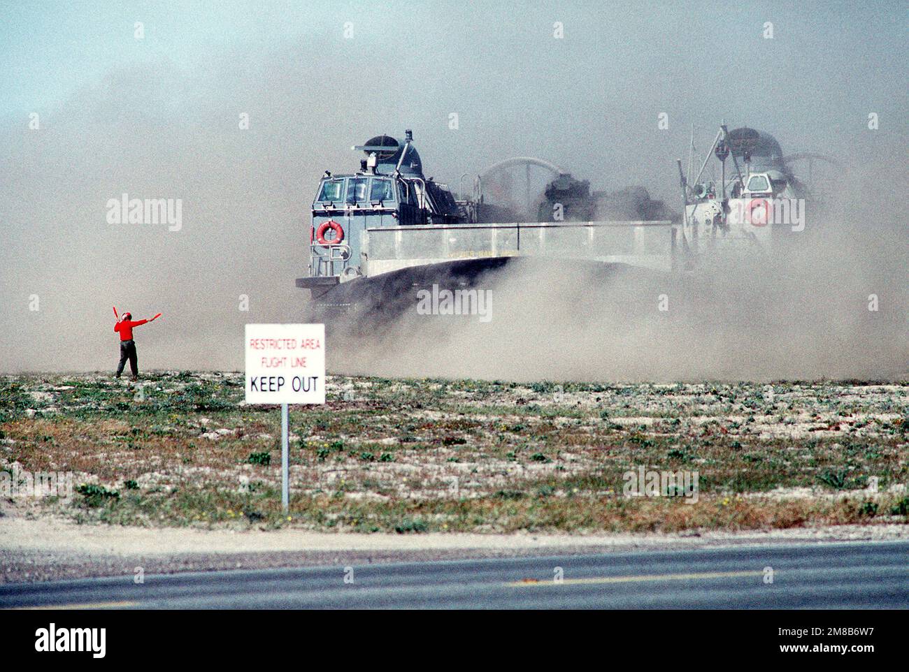 Ein Air Cushion Landing Craft (LCAC) peitscht einen Staubsturm auf, während es während einer amphibischen Kriegsführung am Breakers Beach über ein Feld geführt wird. Basis: Marineflugstation, Nordinsel Bundesstaat: Kalifornien (CA) Land: Vereinigte Staaten von Amerika (USA) Stockfoto