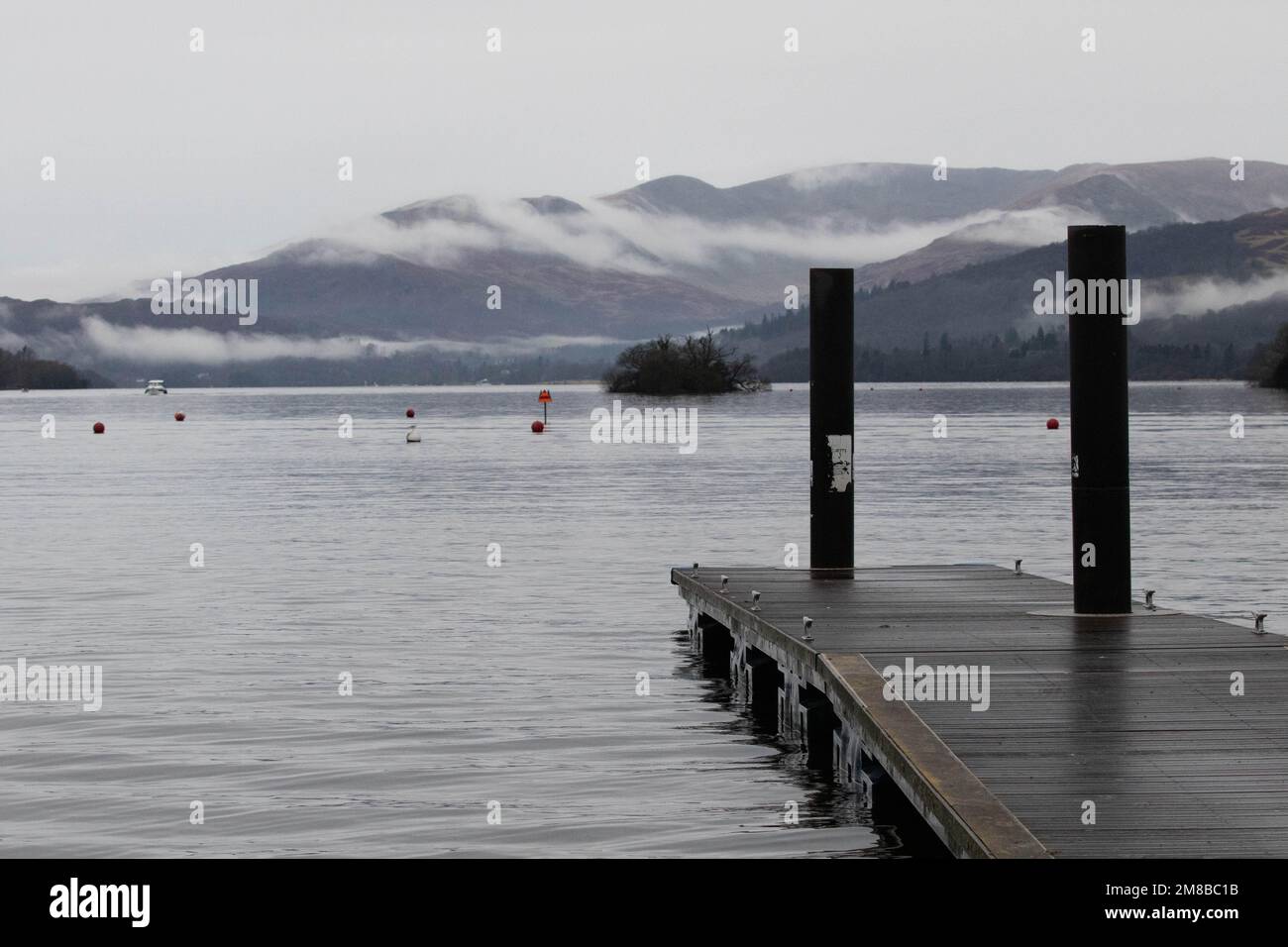 Anlegestelle am Lake Windermere mit Nebel über den Bergen an einem bewölkten Tag Stockfoto