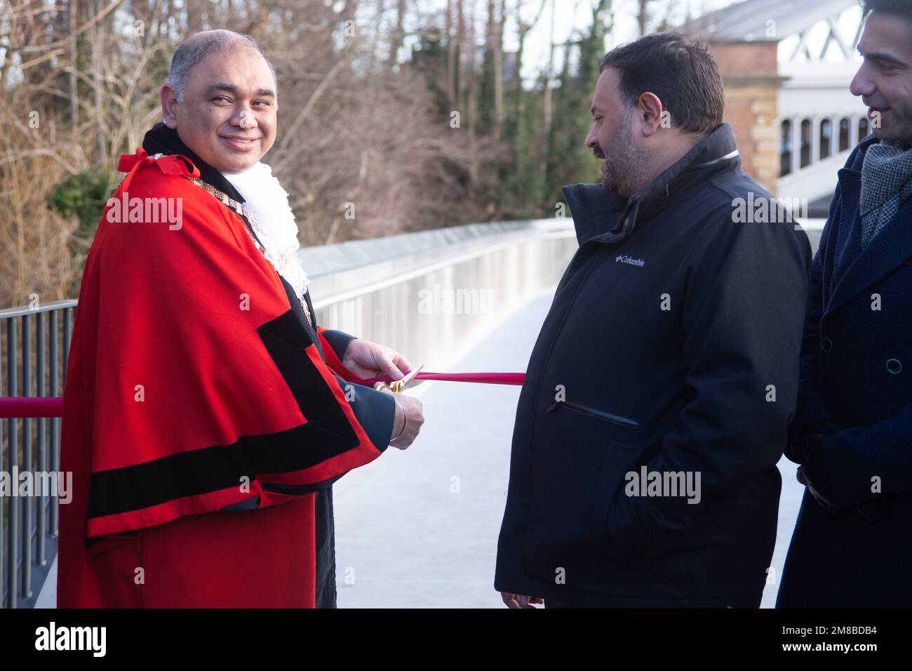 London, Großbritannien. 13. Januar 2023. Die Dukes Meadows Bridge eröffnet Chiswick einen verbesserten Zugang zum Themsenpfad. London, Großbritannien. Hounslows Bürgermeister, Raghwinder Siddhu, in Gewändern. Das 4-jährige Projekt von Stadtrat John Todd von Chiswick wird mit dem Durchschneiden des Bandes durch Hounslow, Bürgermeister Raghwinder Siddhu, verwirklicht. Die Stahlpfanne der Chiswick School und der Theaterkurs waren voller Energie. Toast the Dog war der erste Hund, der die Brücke unter der Barnes Bridge benutzte. Kredit: Peter Hogan/Alamy Live News Stockfoto