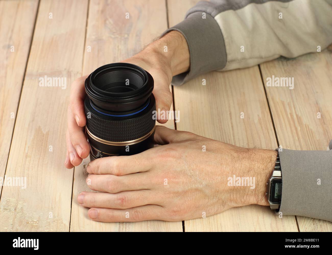 Eine Person, die eine Makrolinse in der Hand auf dem Tisch hält Stockfoto