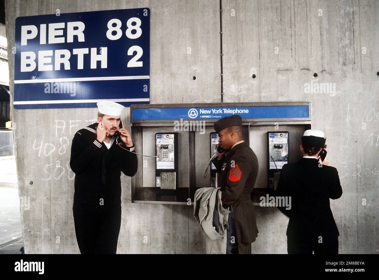 Matrosen und ein Marine telefoniert mit Verwandten und Freunden bei der Ankunft in New York für Flottenwochenaktivitäten. Basis: New York Staat: New York (NY) Land: Vereinigte Staaten von Amerika (USA) Stockfoto