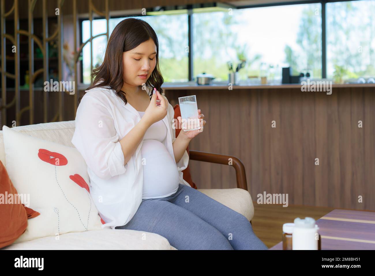 Asiatische Frau schwangere Mutter mit Medikamentenzusatz und Glas Wasser - Einnahme von Vitaminen während der Schwangerschaft Stockfoto