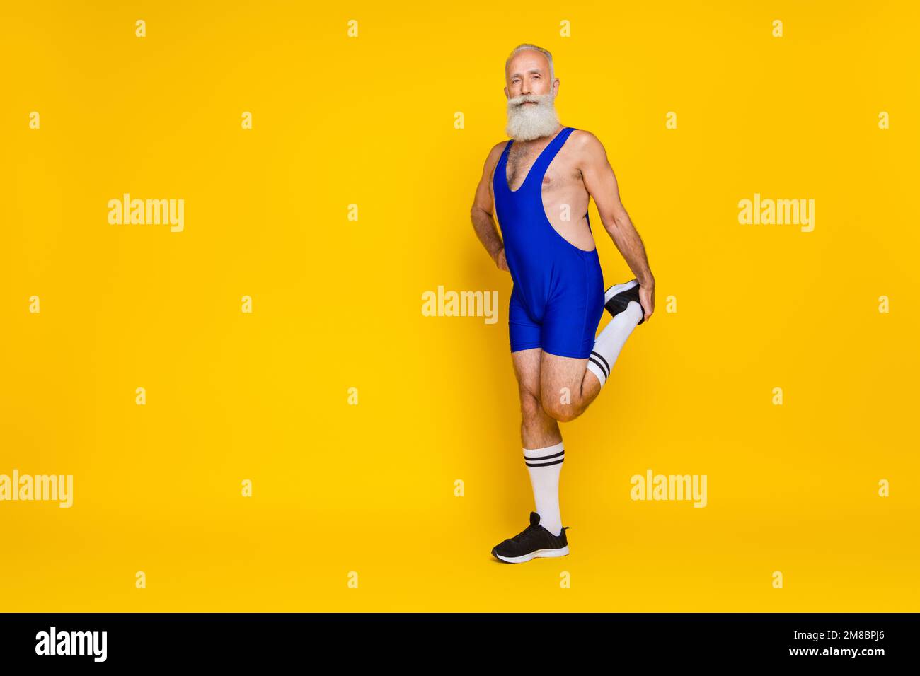 Langes Foto eines energiegeladenen Senior man Coach zum Aufwärmen der Beine Lauf Sprint Marathon Kleidung Anzug leer isoliert auf gelbem Hintergrund Stockfoto