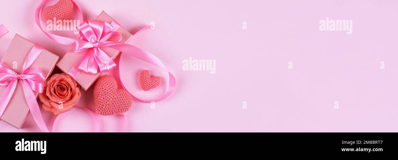 Pinke Rosen, gestrickte pinke Herzen, Geschenkbox mit Satinschleife auf pinkfarbenem Hintergrund. Grußkarte zum Valentinstag, Muttertag und Geburtstag Stockfoto