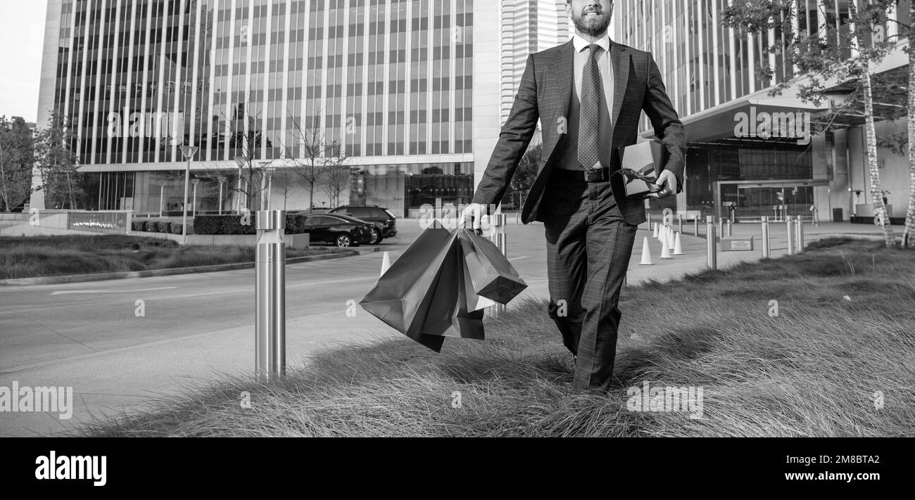 Der in Anzug geschnittene Geschäftsmann hält Pakete und Geschenkkartons außerhalb des Büros, Kopierer, Herrentag Stockfoto