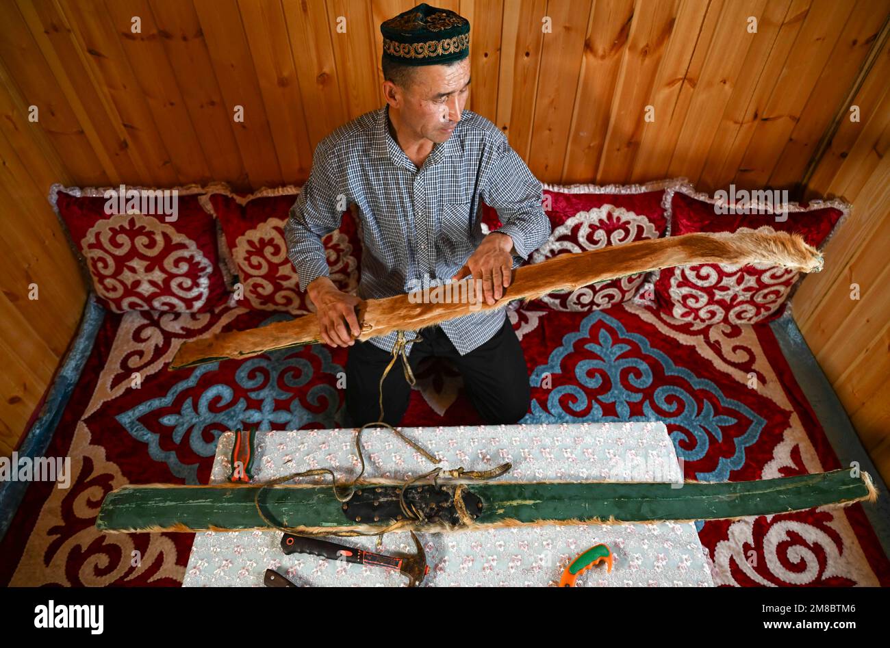 (230113) -- ALTAY, 13. Januar 2023 (Xinhua) -- Ein Hirte zeigt ein Paar fellbedeckte Skier zu Hause in der Präfektur Altay, Nordwestchina, Uygur Autonomous Region Xinjiang, 22. Dezember 2022. Die Präfektur Altay ist bekannt für ihre lange Wintersaison, die bis zu acht Monate pro Jahr dauern kann. Mit seinem weitläufigen natürlichen Pulverschnee zieht es Skifahrer weltweit an. Die Region hat sich in den letzten Jahren bemüht, den Wintertourismus anzukurbeln und Besucher mit Skifahren, Eisangeln und anderen Winteraktivitäten zu verführen. Zwischen dem 2022. Dezember und dem 11. Januar 2023 wurden rund 1,02 Millionen Touristen aufgenommen. (Xinhua/Hu Huhu) Stockfoto