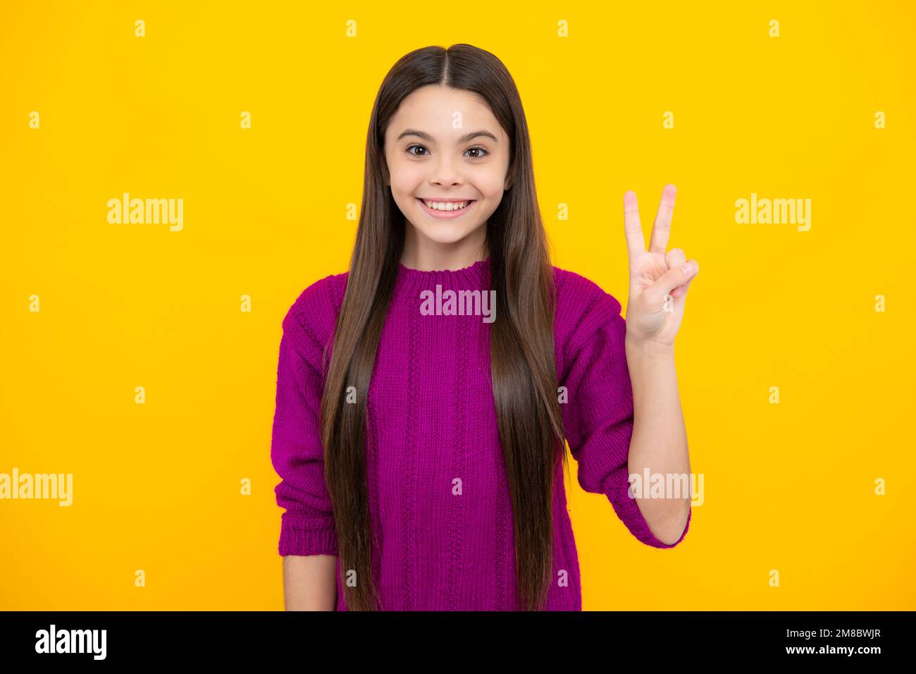 Teenager Kind Mädchen zeigt Finger Siegeszeichen. Nummer zwei, auf gelbem Hintergrund isoliertes V-Zeichen-Symbol. Stockfoto