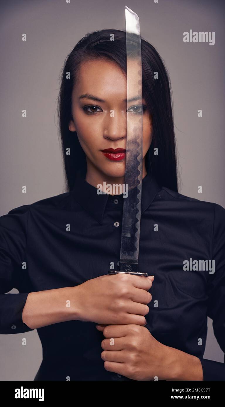 Porträt, Schwert und Krieger mit einer asiatischen Frau im Studio auf grauem Hintergrund für Kampfsport oder Kampf. Training, Fantasie und Waffe mit einem Ninja Stockfoto