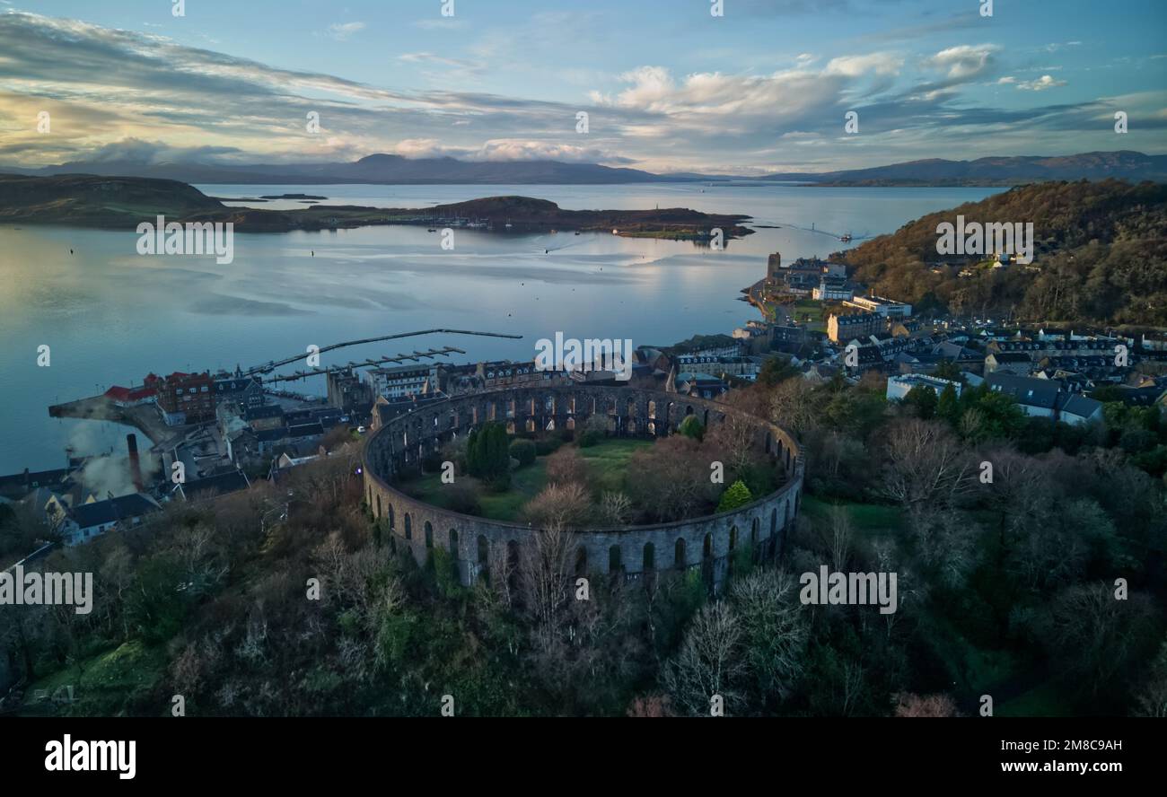 Blick über Oban und Oban Bay, McCaig's Tower im Vordergrund, Argyll, Schottland bei Sonnenuntergang Stockfoto