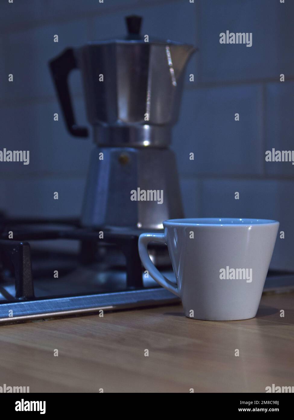 Moka Kanne auf Küchenherd mit Kaffeetasse auf Arbeitsplatte Stockfoto