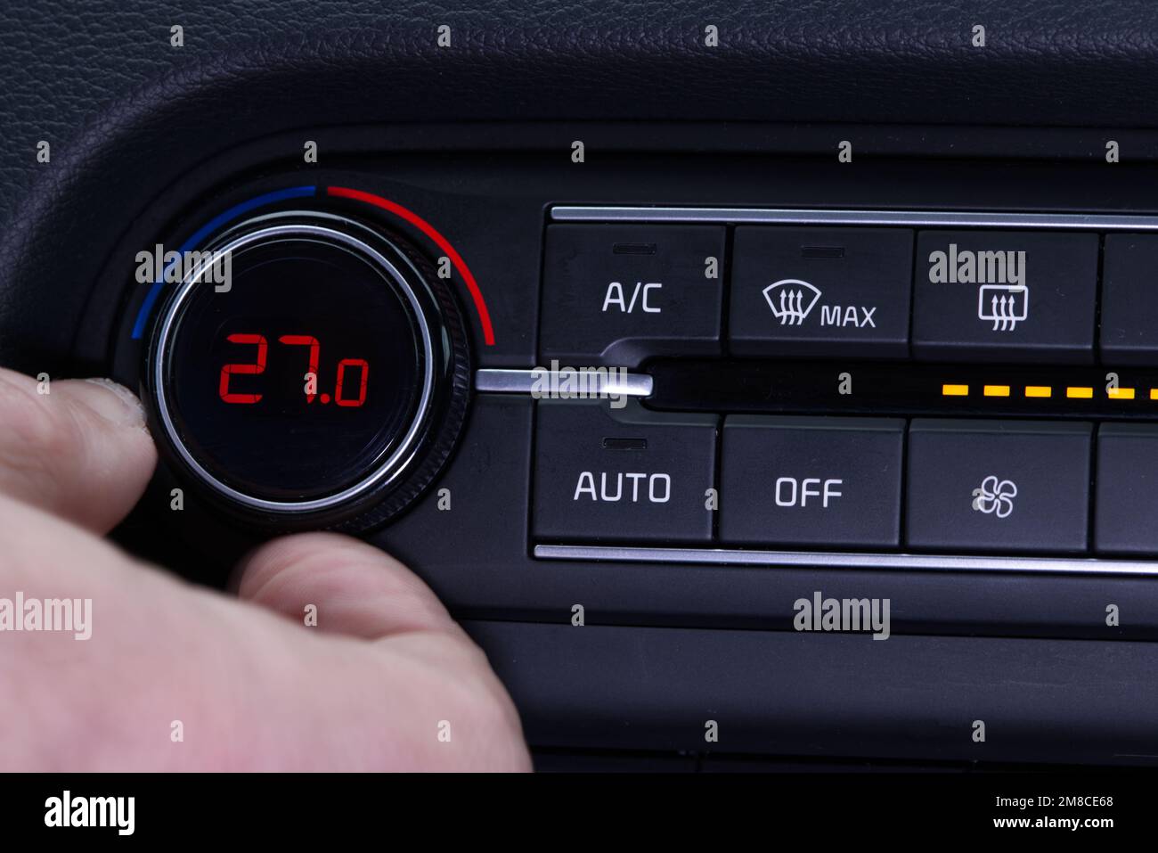 Stellen Sie die Klimaanlage im Auto auf. Die Hand dreht den Klimaanlagenring. Das Display zeigt eine Temperatur von 27,0 Grad celsius im Fahrzeug an. Kühlluft in t Stockfoto