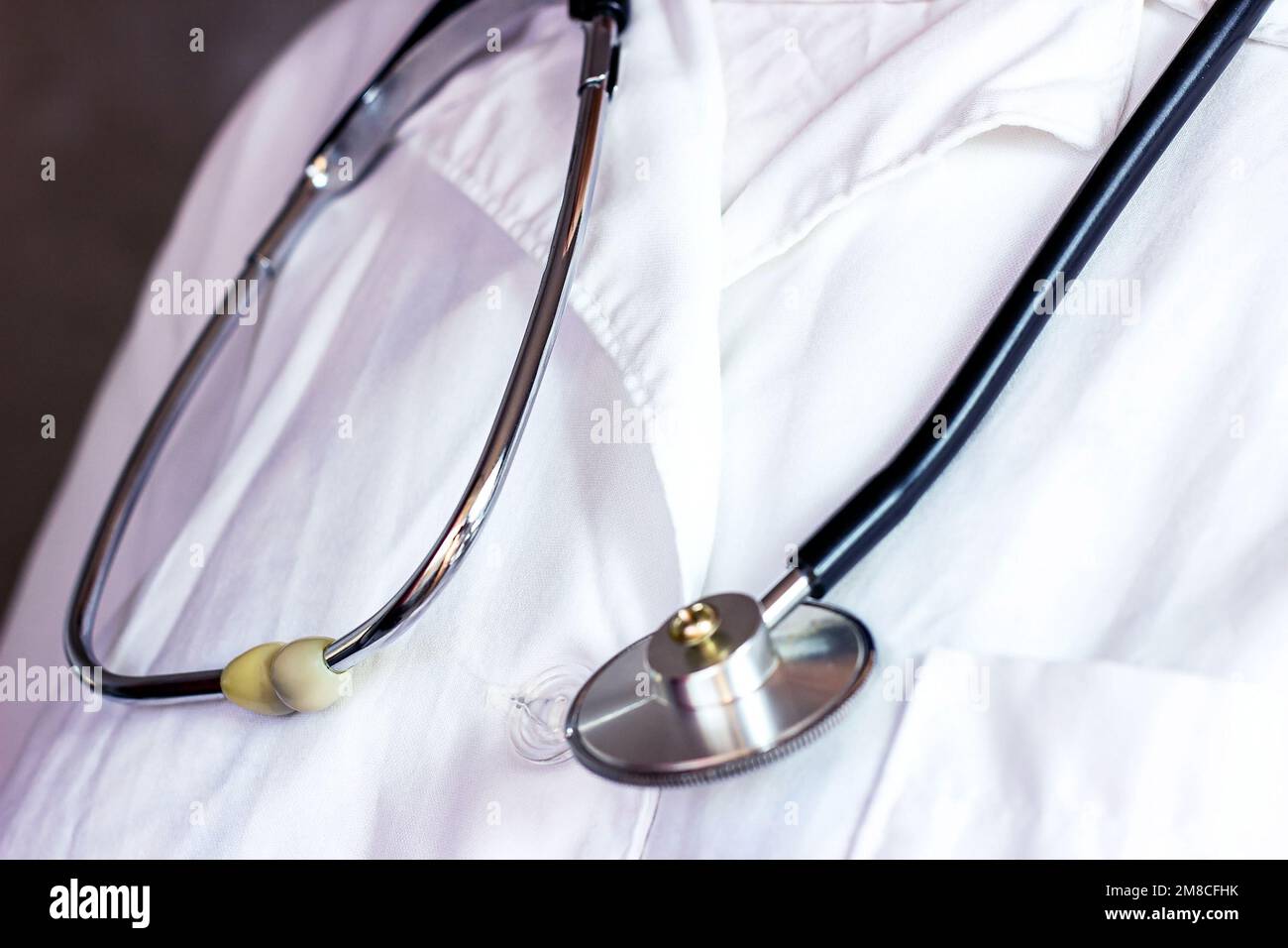 Schwarzes Metall-medizinisches Stethoskop auf weißer Arztuniform im Krankenhaus. Stockfoto