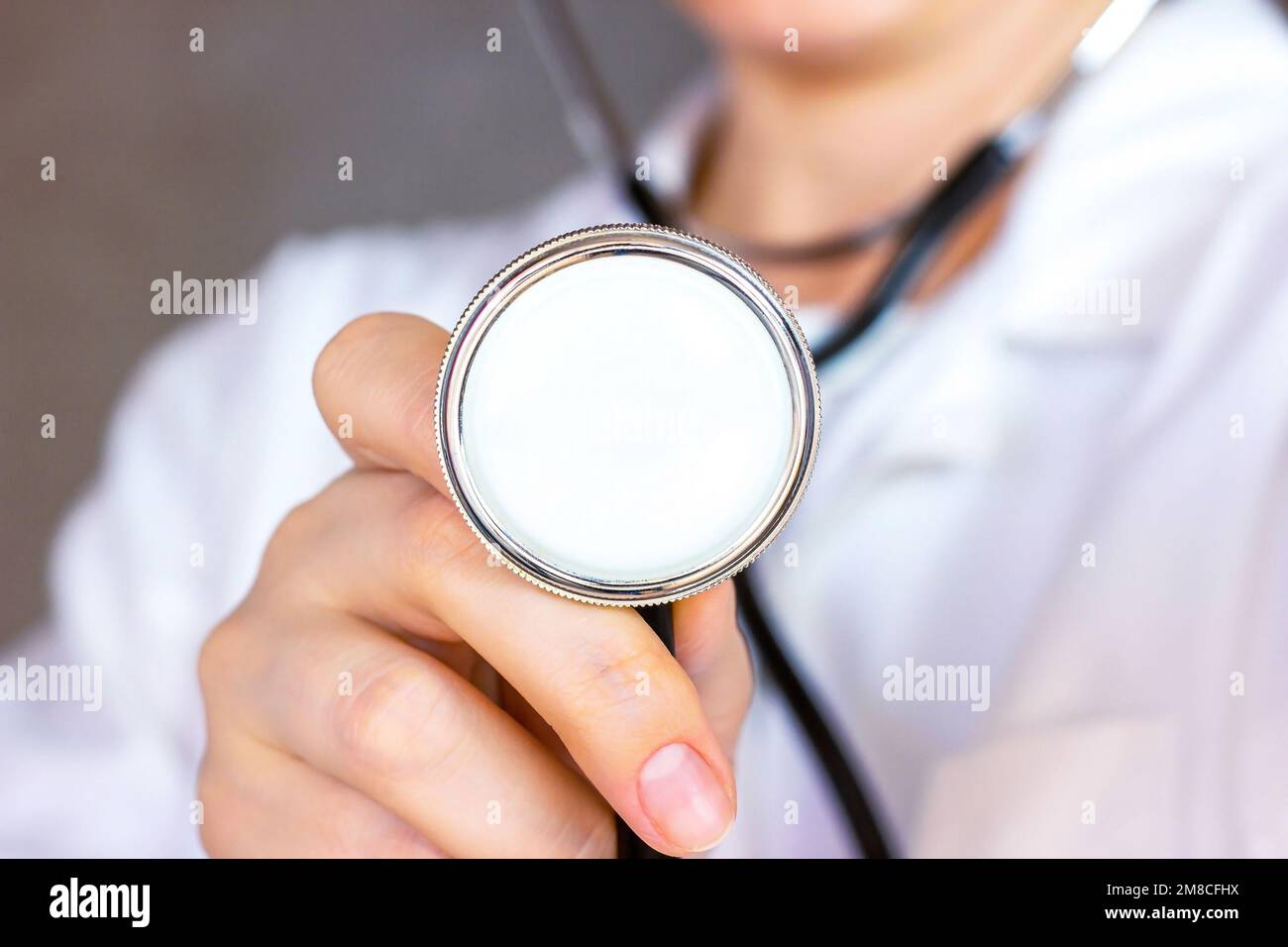 Weiße Frau in weißer Arztuniform hält ein Stethoskop in der Hand für eine medizinische Herzuntersuchung. Stockfoto