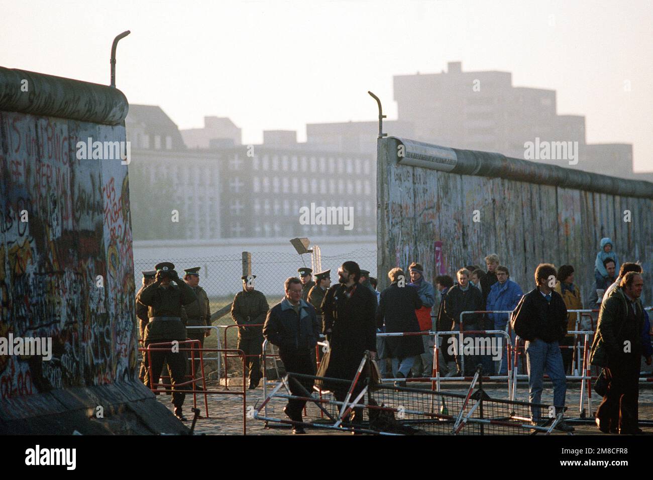 Die ostdeutsche Polizei beobachtet, wie Besucher die neu geschaffene Öffnung an der Berliner Mauer am Potsdamer Platz passieren. Basis: Berlin Land: Deutschland / Deutschland (DEU) Stockfoto