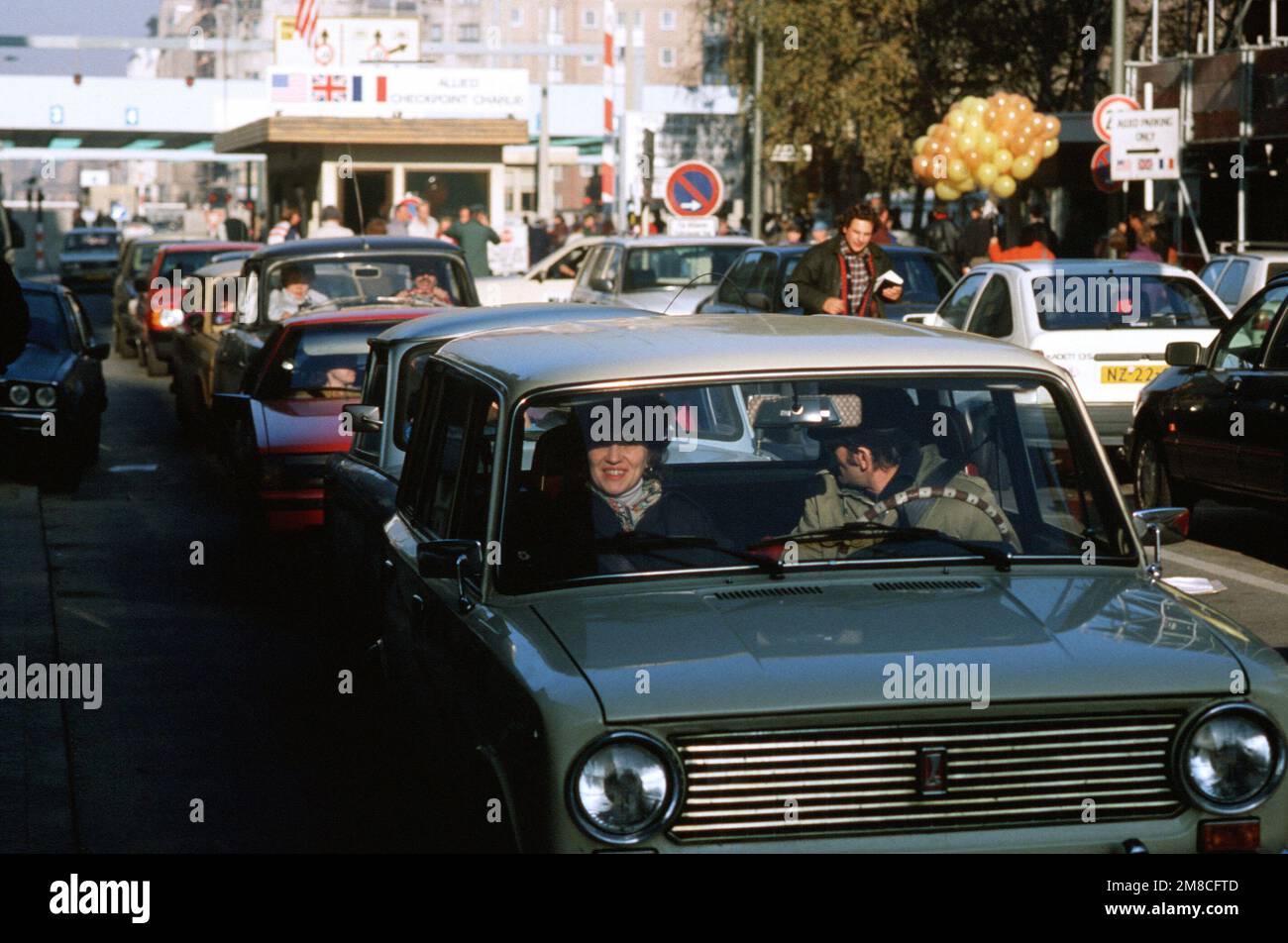 Ostdeutscher fahren mit ihrem Auto durch Checkpoint Charlie und nutzen die lockeren Reisebeschränkungen für einen Besuch in Westdeutschland. Basis: Berlin Land: Deutschland / Deutschland (DEU) Stockfoto