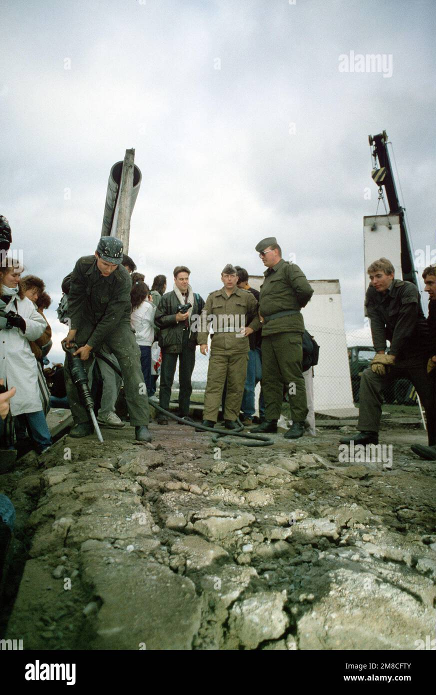 Die ostdeutsche Polizei und westdeutsche Bürger beobachten, wie ein Arbeiter einen Abschnitt der Berliner Mauer am Potsdamer Platz demontierte. Basis: Berlin Land: Deutschland / Deutschland (DEU) Stockfoto