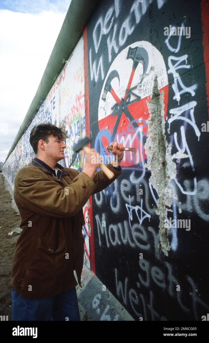 Ein westdeutscher Mann verwendet Hammer und Meißel, um ein Stück der Berliner Mauer als Souvenir abzuschlagen. Ein Teil der Mauer wurde bereits am Potsdamer Platz abgerissen. Basis: Berlin Land: Deutschland / Deutschland (DEU) Stockfoto