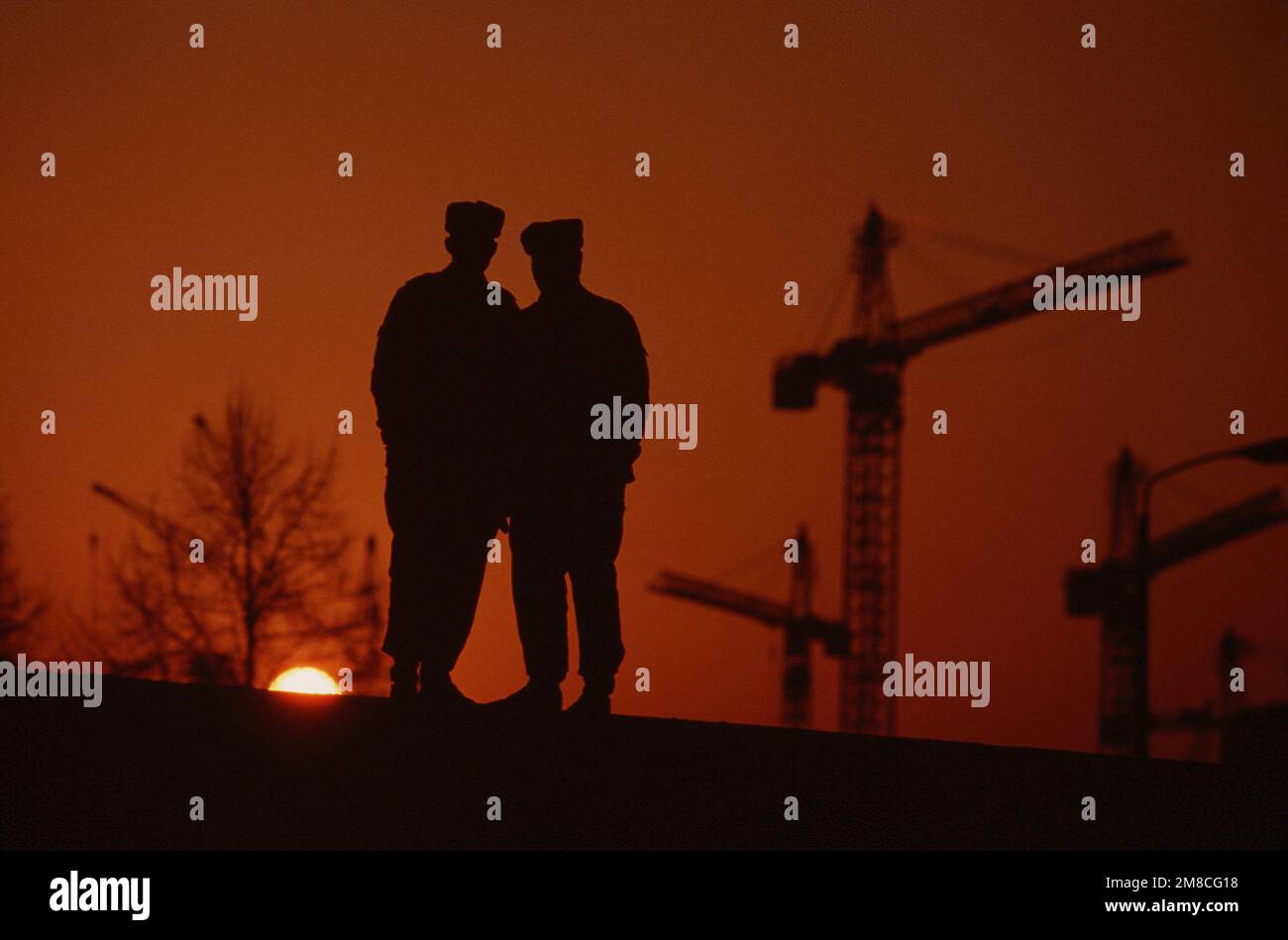 Ostdeutsche Polizisten stehen bei Sonnenuntergang auf einem Abschnitt der Berliner Mauer. Basis: Berlin Land: Deutschland / Deutschland (DEU) Stockfoto