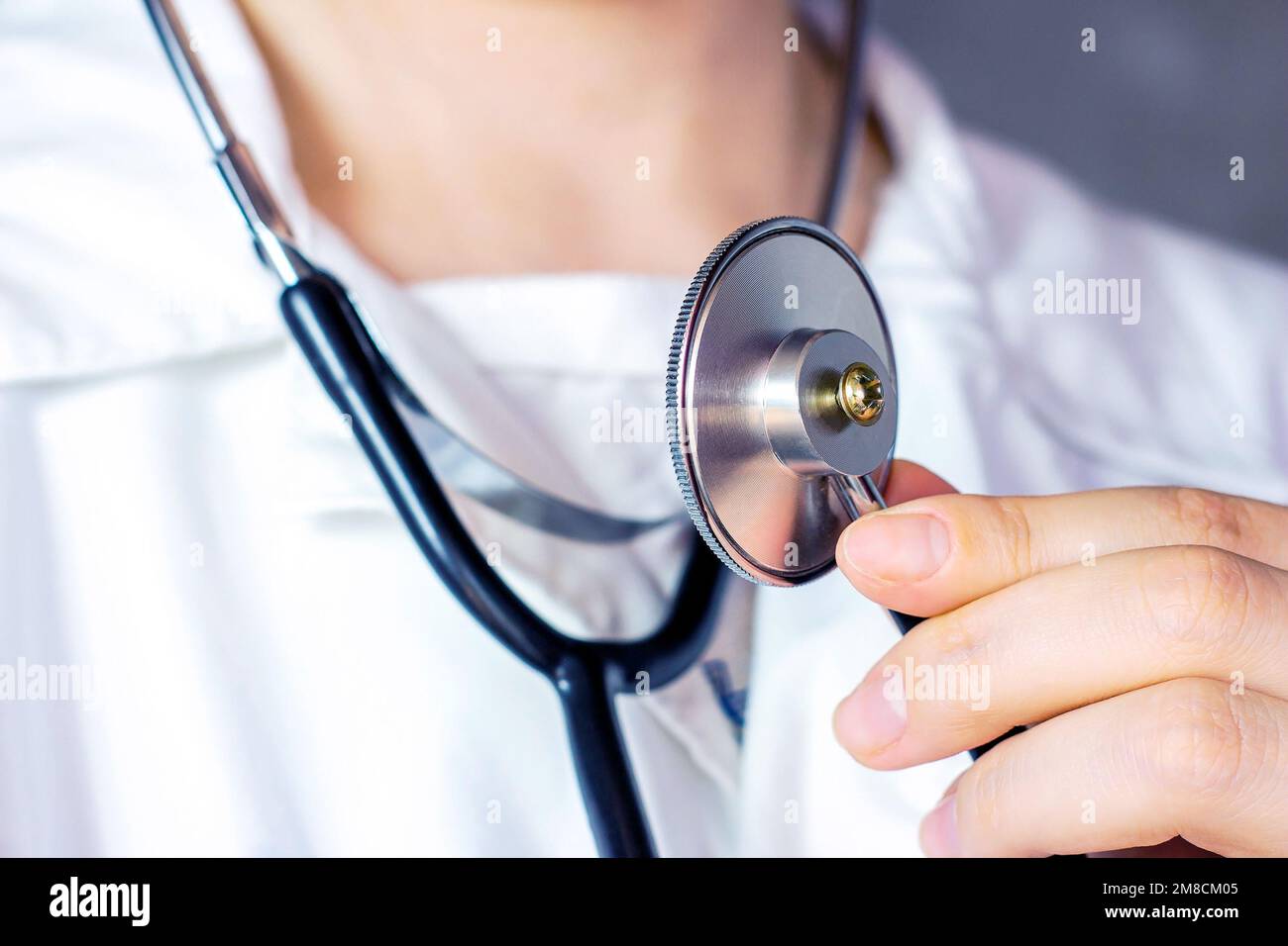 Weiße Frau in weißer Arztuniform hält ein Stethoskop in der Hand für eine medizinische Herzuntersuchung. Stockfoto