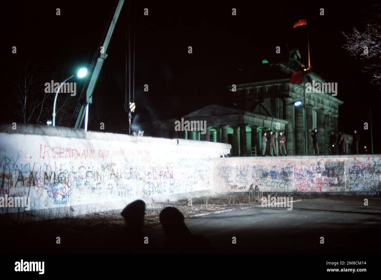 Die ostdeutschen Wachen beobachten, wie sich ein Kran darauf vorbereitet, einen Abschnitt der Berliner Mauer neben dem Brandenburger Tor zu entfernen. Basis: Berlin Land: Deutschland / Deutschland (DEU) Stockfoto