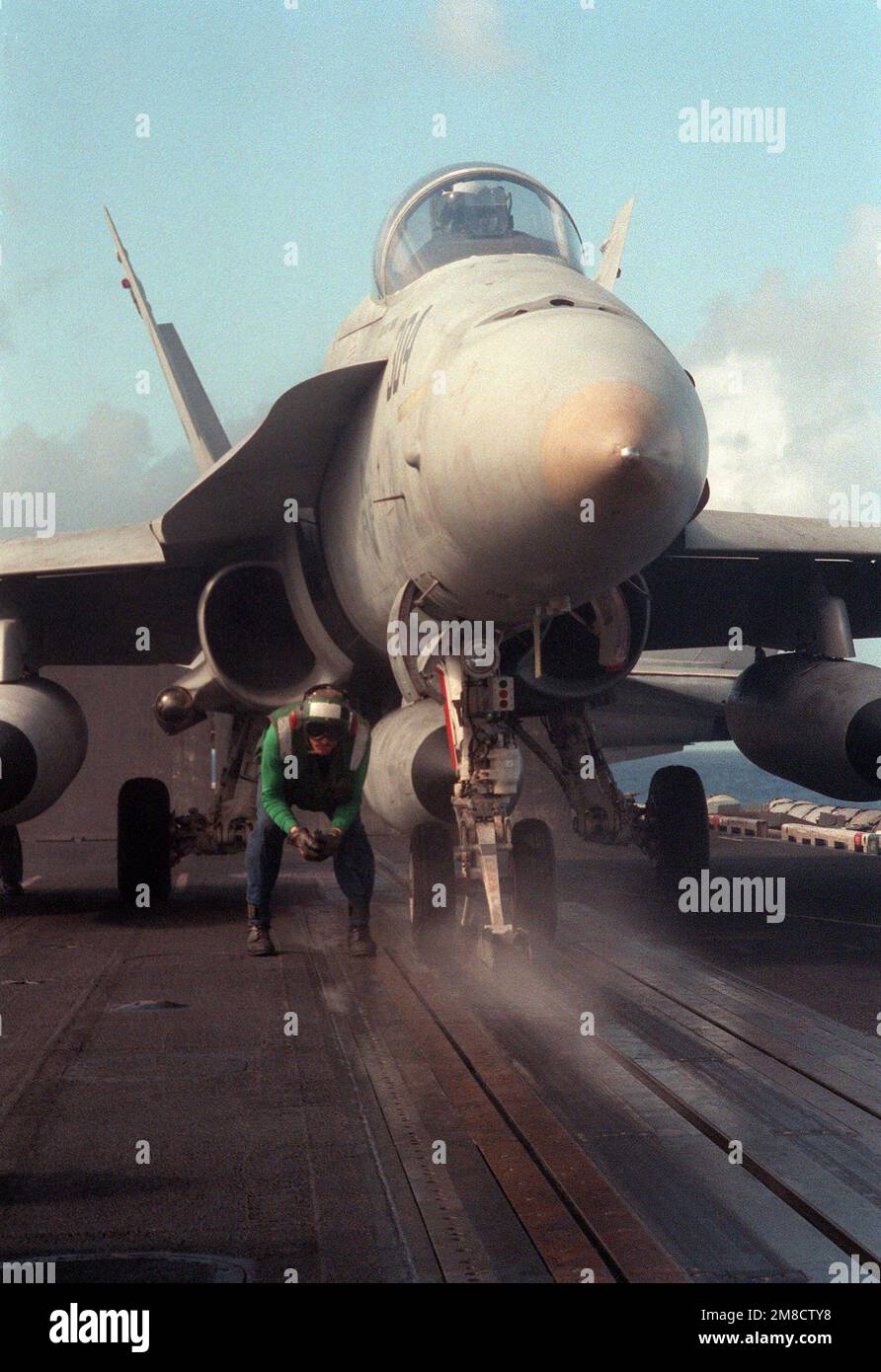 Ein Katapult-Crewman wartet darauf, dass das Shuttle vollständig zurückgezogen ist, bevor er die Nasenausrüstung eines Strike Fighter Squadron 136 (VFA-136) F/A-18A Hornet-Flugzeugs an Bord des nuklearbetriebenen Flugzeugträgers USS DWIGHT D. EISENHOWER (CVN-69) während der Flotte Ex '90 anschließt. Betreff Betrieb/Serie: FLOTTE EX '90 Land: Atlantik (AOC) Stockfoto