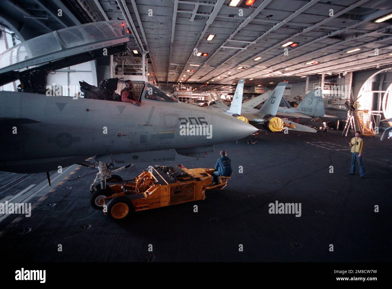 Das Personal am Hangar Deck verwendet einen SD-1D-Spürhund, um ein Kampfgeschwader 142 (VF-142) F-14A Tomcat aus einem Aufzug an Bord des nuklearbetriebenen Flugzeugträgers USS DWIGHT D. EISENHOWER (CVN-69) während DER FLOTTE EX '90 zu transportieren. Betreff Betrieb/Serie: FLOTTE EX '90 Land: Atlantik (AOC) Stockfoto