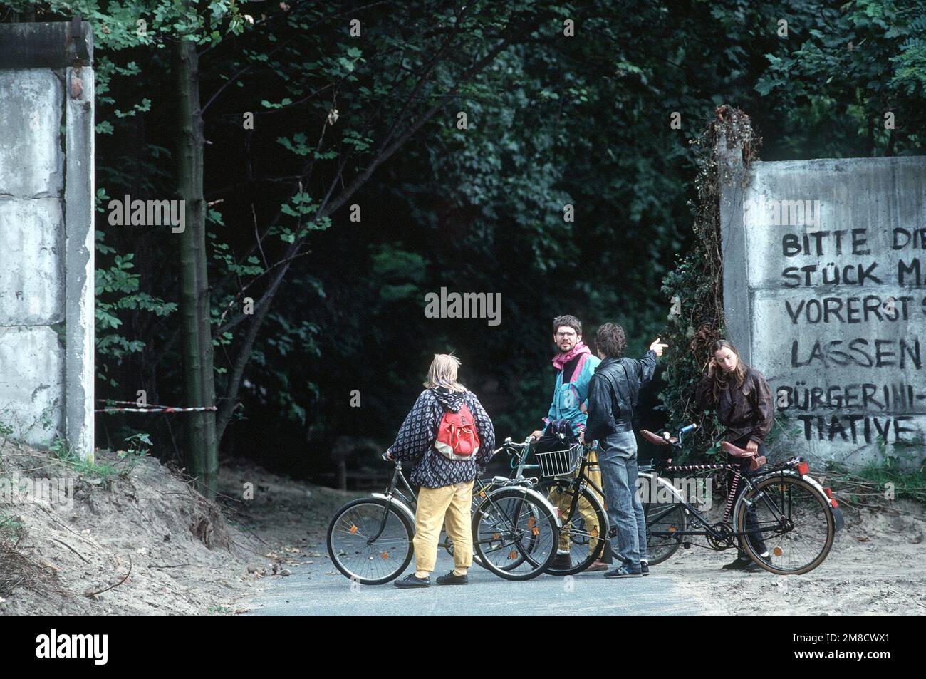 Radfahrer machen nach der Wiedervereinigung Deutschlands eine Pause in der Nähe eines verbleibenden Abschnitts der Berliner Mauer. Basis: Berlin Land: Deutschland / Deutschland (DEU) Stockfoto