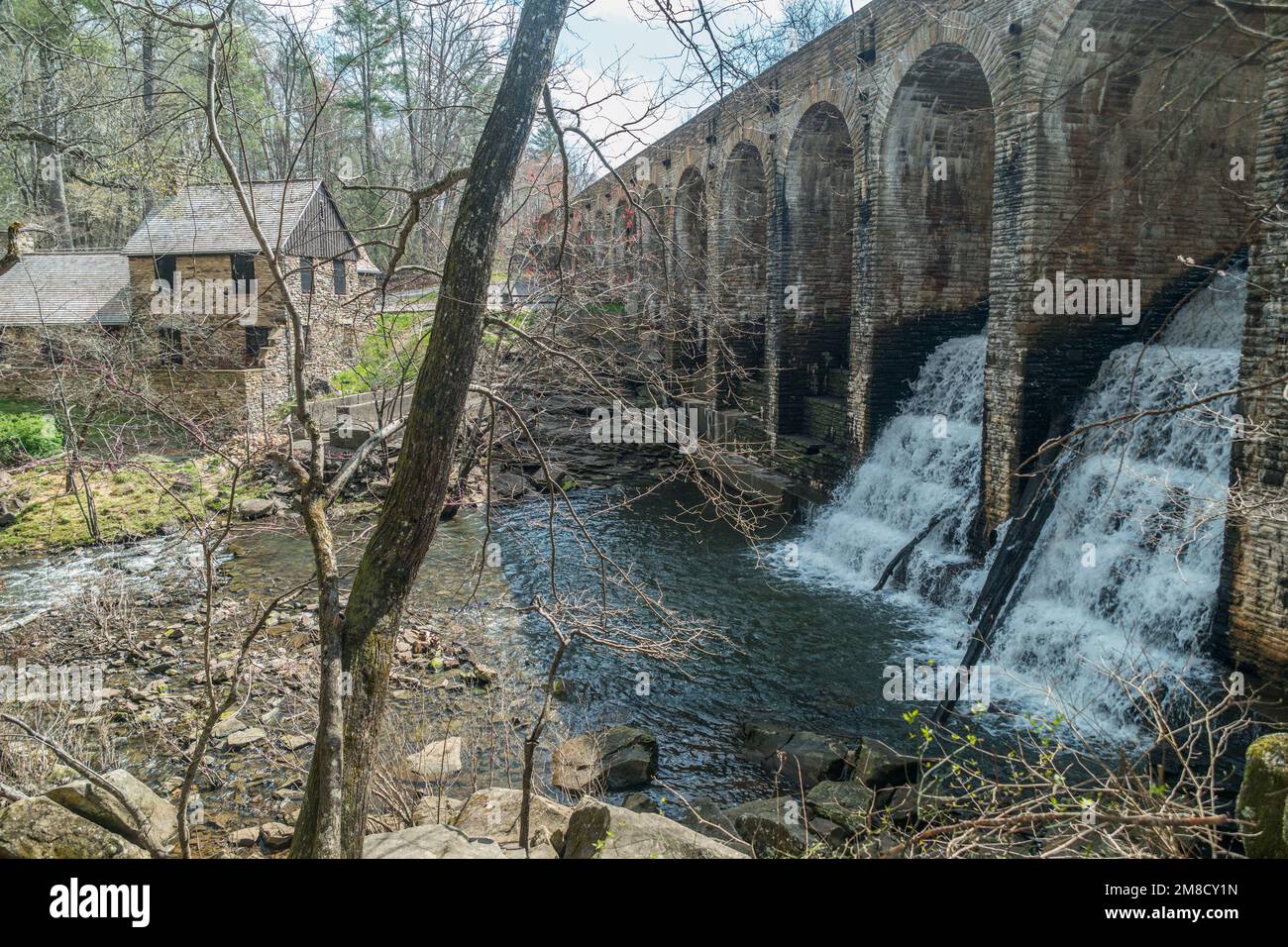 Auf der anderen Seite der Steinbrücke mit nach unten fließendem Wasser befindet sich ein Damm mit dem Mühlenhaus Lodge im Hintergrund am Cumberland Mountain Stockfoto