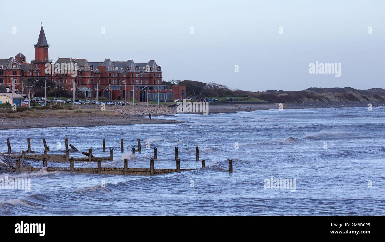 Newcastle, County Down, Nordirland, Großbritannien. 13. Januar 2023 Wetter im Vereinigten Königreich: Nach den heftigen Winden und Warnungen von gestern ist die Lage etwas zurückgegangen. Es ist sehr luftig und muffig an exponierten Küsten wie hier an der Küste von Newcastle. Leute am Strand von Newcastle im Winter vor dem Slieve Donard Hotel. Kredit: David Hunter/Alamy Live News. Stockfoto