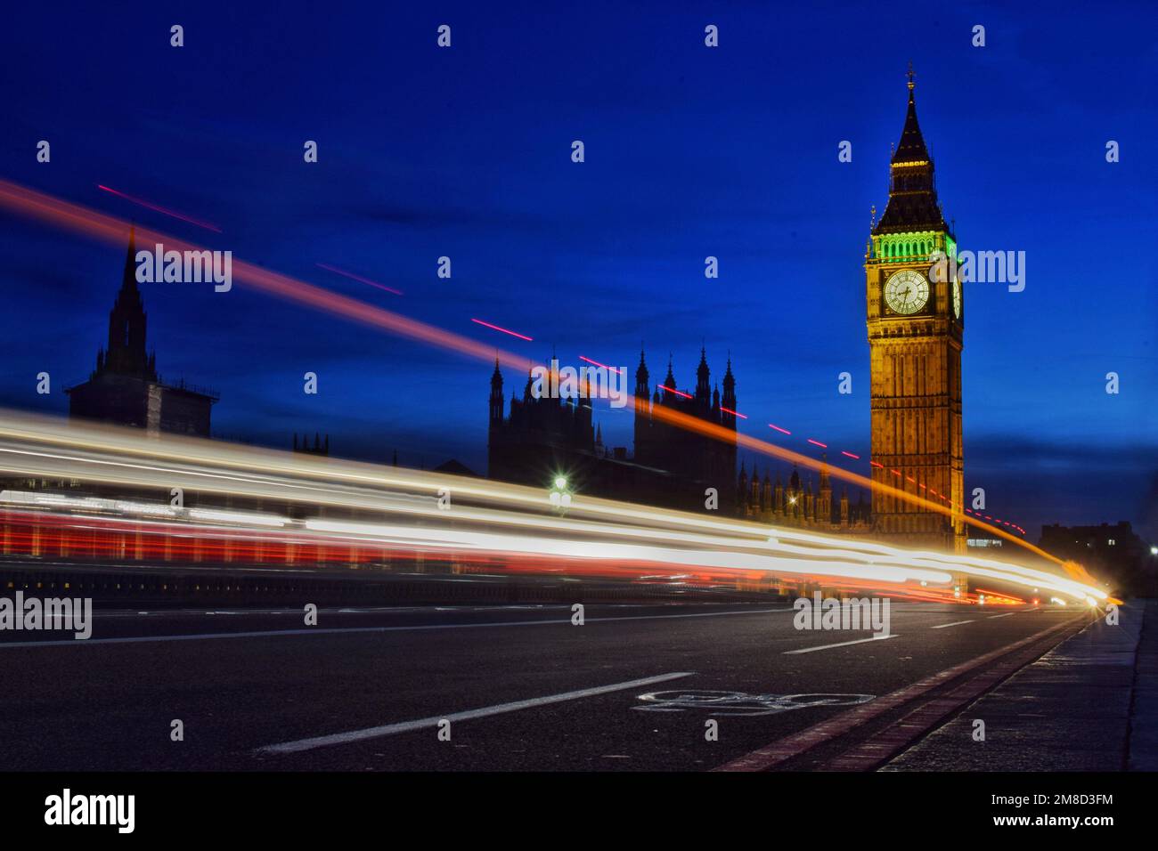 Long Exposure Nachtaufnahme von Big Ben mit vorbeifahrenden Zügen und Autos in London Stockfoto