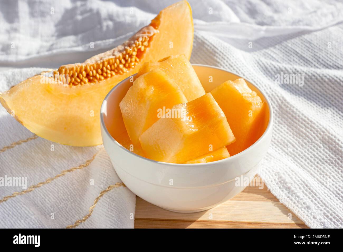 Frische süße, saftige Honigmelone (Cantaloupe) in Scheiben in einer weißen Schüssel in der Küche im Sommer. Stockfoto